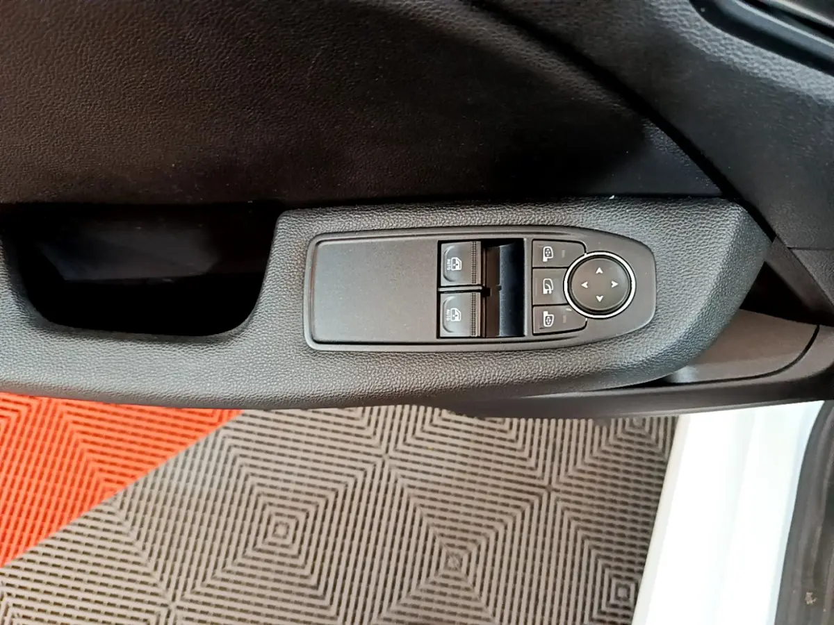 Gros plan sur la commande des vitres et rétroviseurs côté conducteur d'une Renault Clio Business blanche, intérieur noir.