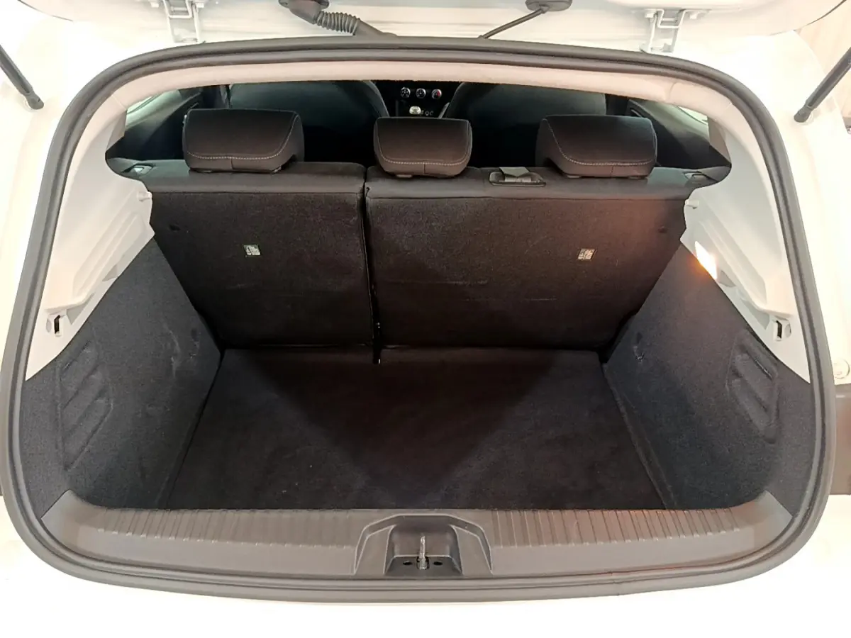 Coffre ouvert vu de l'arrière d'une Renault Clio Business blanche, montrant la banquette arrière et l'espace de chargement.