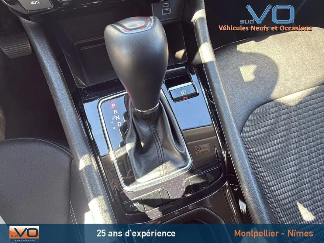 Gros plan sur la console centrale du Jeep Compass gris 2023 avec levier de vitesse automatique et accoudoir cuir noir.