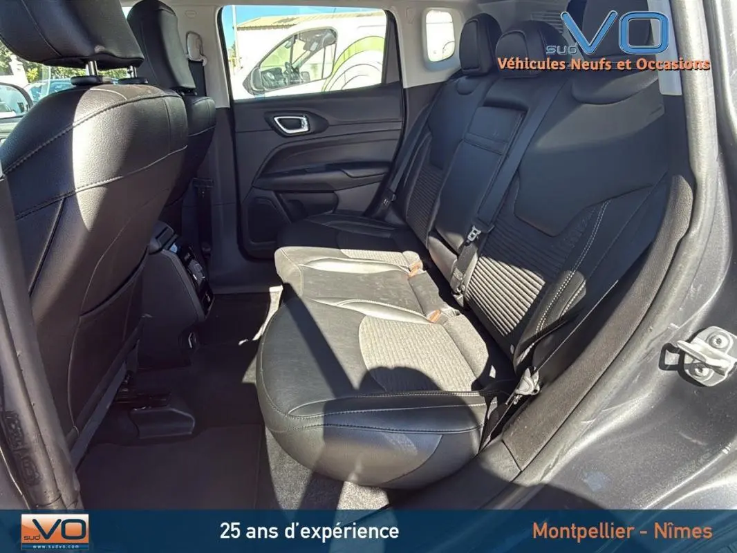 Vue intérieure arrière droite du Jeep Compass gris 2023, montrant les sièges arrière en cuir et tissu avec accoudoir central.