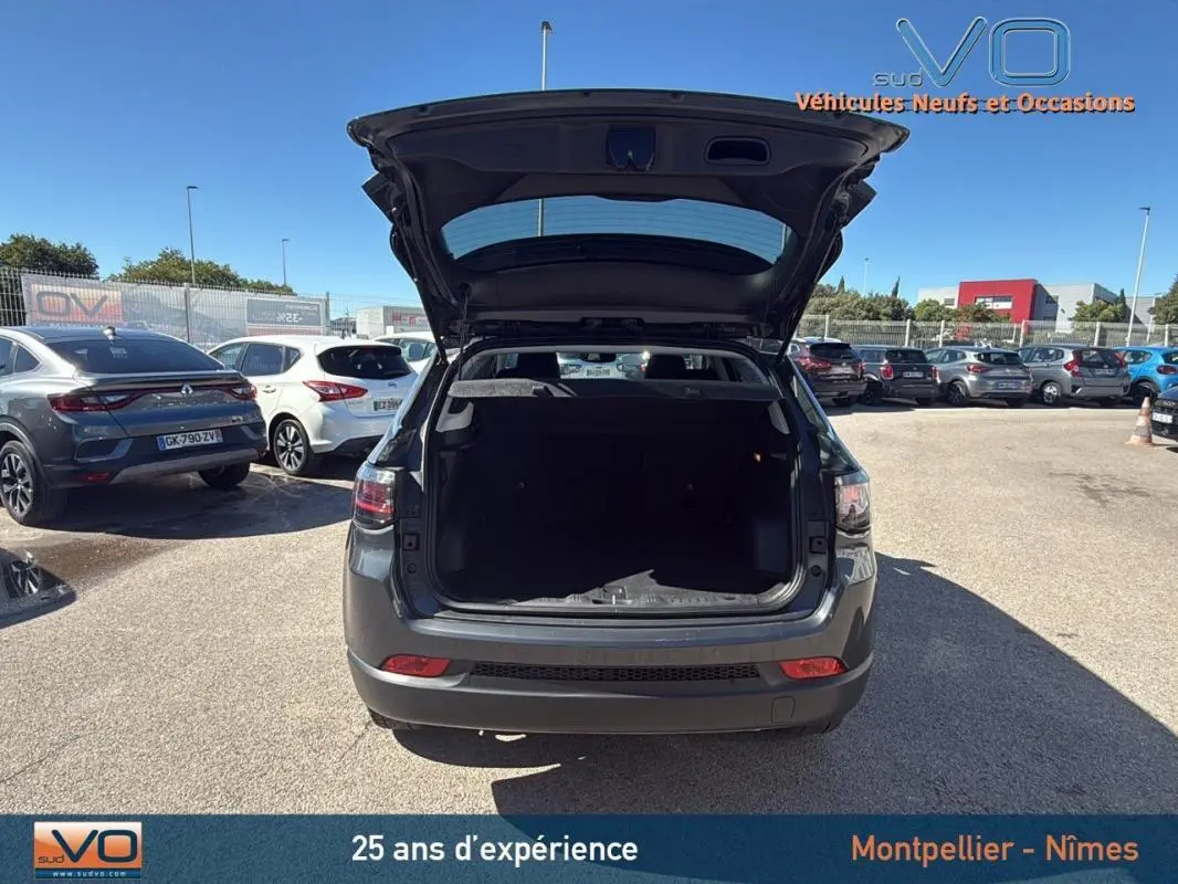 Vue arrière d’un Jeep Compass gris 2023 avec coffre ouvert, montrant l’espace de chargement vide et les feux arrière LED.