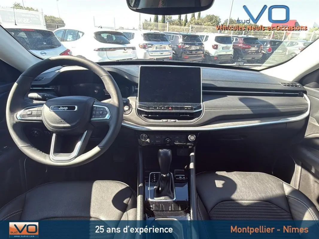 Intérieur du Jeep Compass gris 2023, vue frontale du tableau de bord avec écran tactile et volant multifonction.