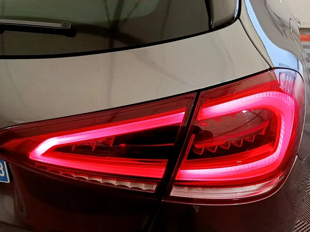 Gros plan sur le feu arrière droit rouge allumé d’une Mercedes Classe A hybride rechargeable couleur sombre.