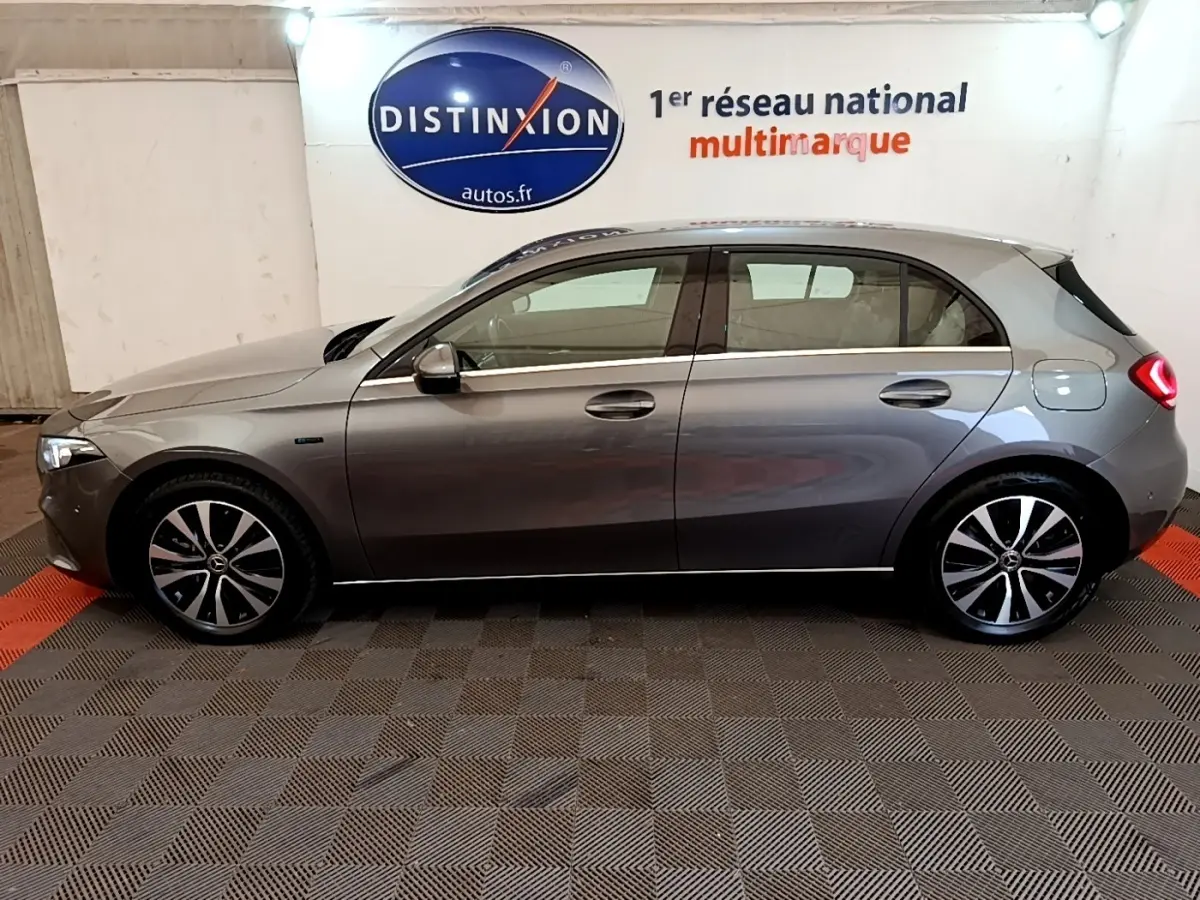 Vue latérale droite d'une Mercedes Classe A A 250 e Business Line grise, avec jantes alliage et feux arrière allumés.