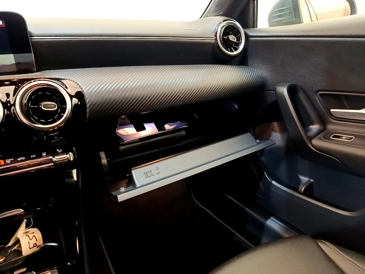 Vue intérieure côté passager de la Mercedes Classe A 250 e Business Line 2020, tableau de bord noir avec boîte à gants ouverte.