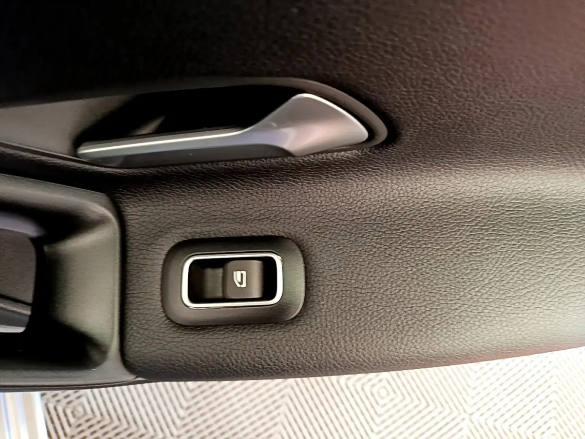 Gros plan sur la poignée intérieure et bouton de verrouillage de porte côté gauche, garniture noire texturée Mercedes Classe A 250 e.