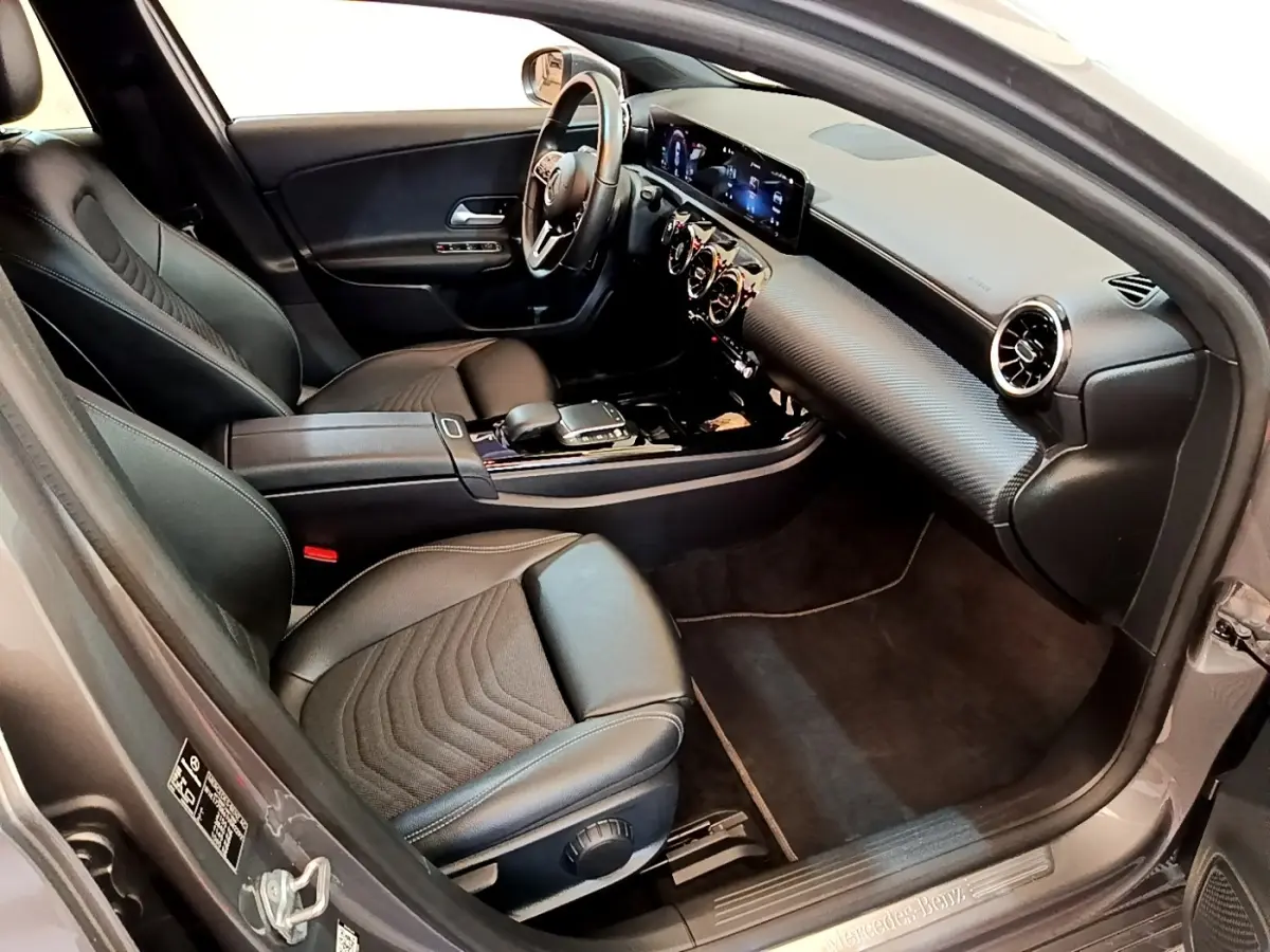 Vue intérieure côté conducteur de la Mercedes Classe A 250 e Business Line 2020 avec sièges cuir noirs et tableau de bord digital.