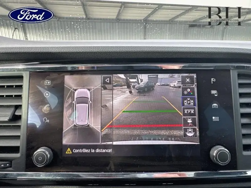 Vue écran caméra 360° et recul du tableau de bord d'une SEAT Ateca blanc Nevada, avec lignes de guidage colorées.