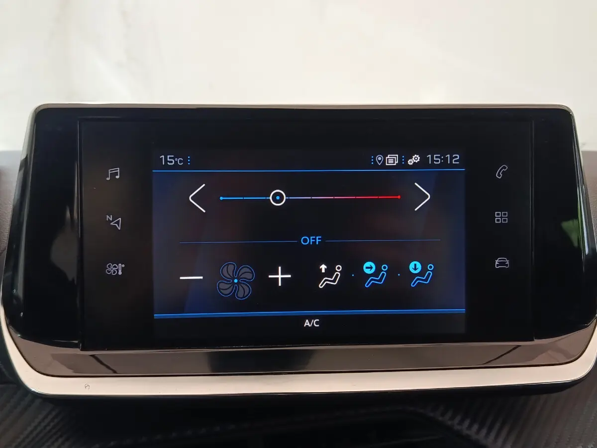 Écran tactile de climatisation du tableau de bord de la Peugeot 208 blanche, affichage digital clair.