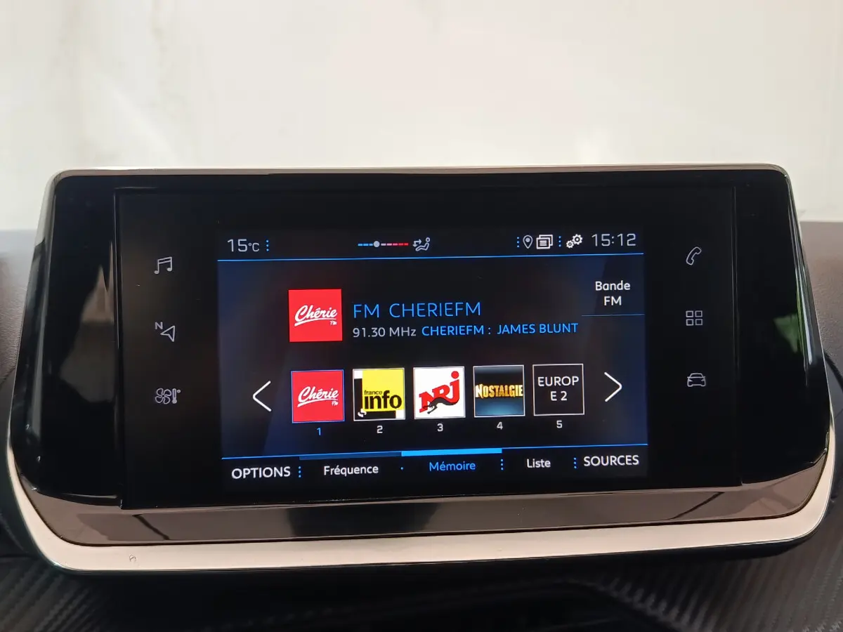 Écran tactile central de 7 pouces du Peugeot 208 blanc, affichant la radio FM avec stations et température extérieure.