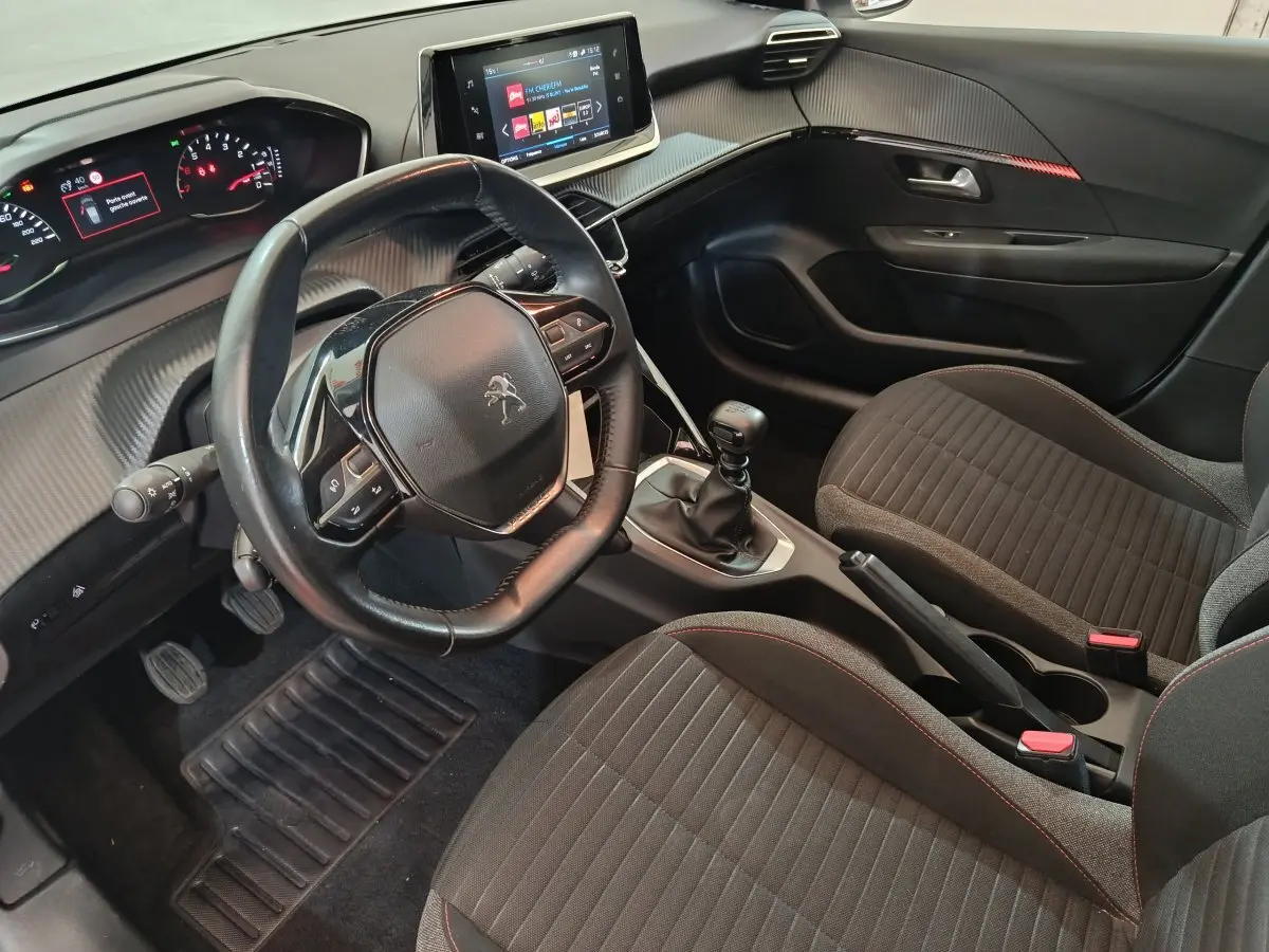Intérieur noir de la Peugeot 208 PureTech 100 S&S Active Business, vue côté conducteur avec volant cuir et écran tactile central.