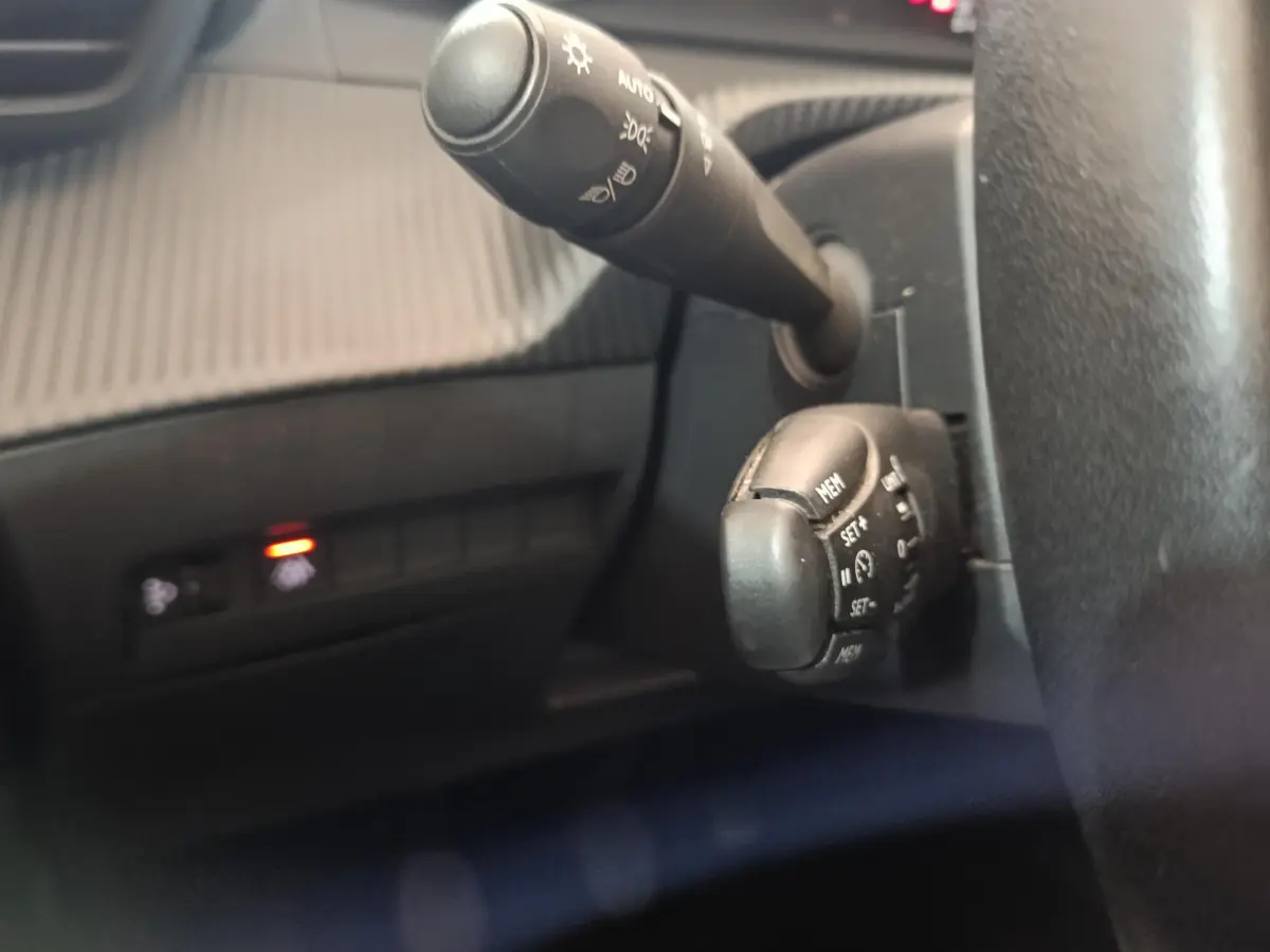 Gros plan sur les commandes au volant et la manette d'éclairage du tableau de bord d'une Peugeot 208 blanche de 2020.