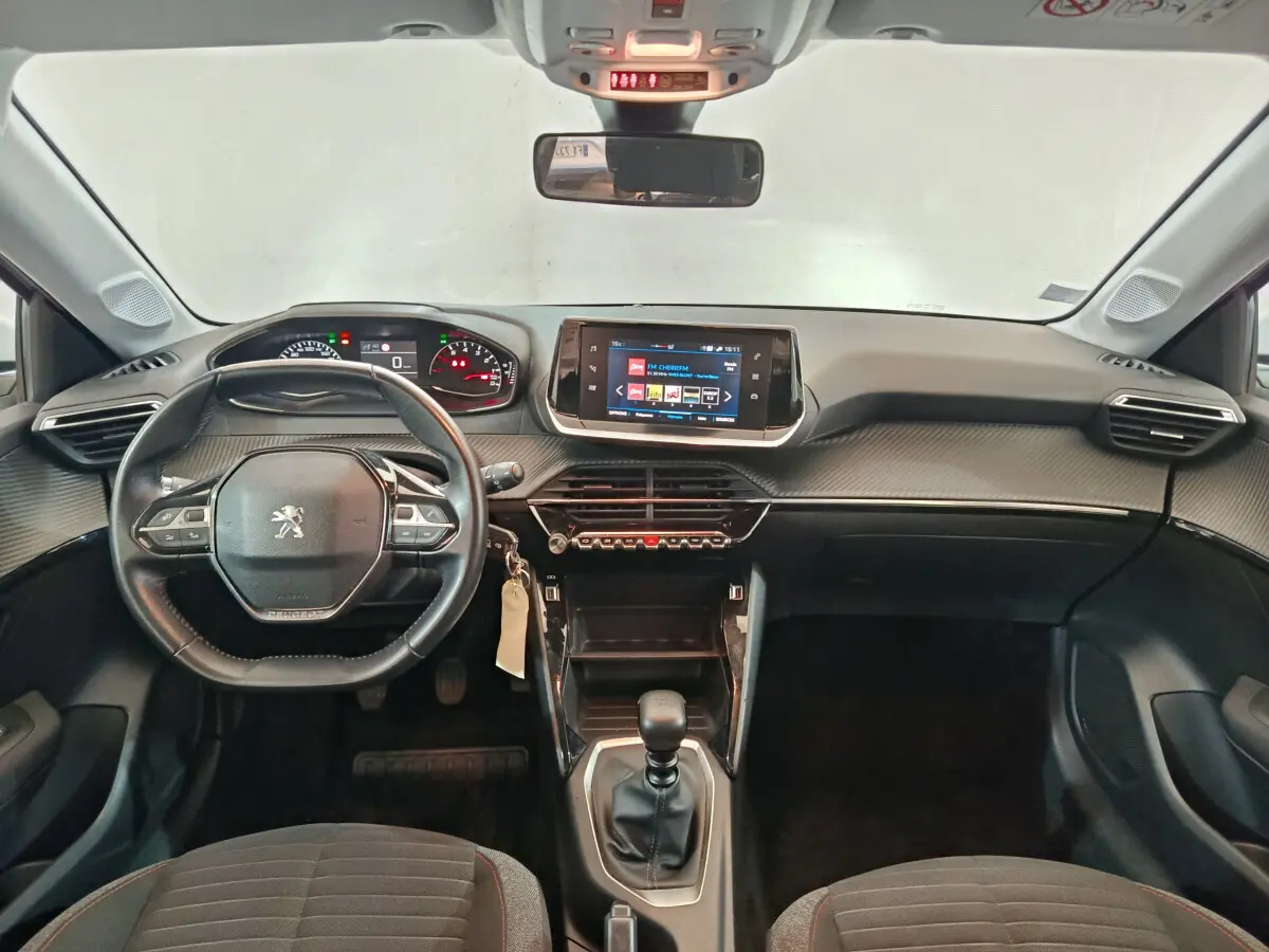 Vue frontale de l'intérieur noir du Peugeot 208 PureTech 100 S&S Active Business avec volant cuir et écran tactile central.