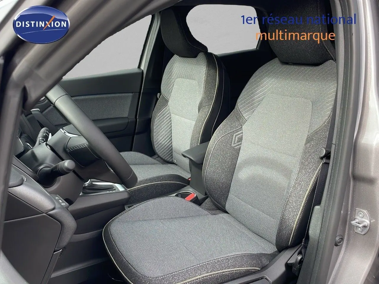 Intérieur du Renault Captur E-Tech hybride 2025, sièges avant en tissu gris avec surpiqûres contrastantes, vue côté conducteur.