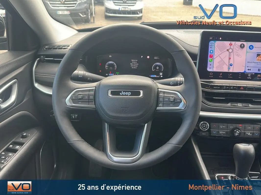 Vue intérieure centrée sur le volant Jeep Compass bleu 2023 avec écran tactile et commandes au volant visibles.