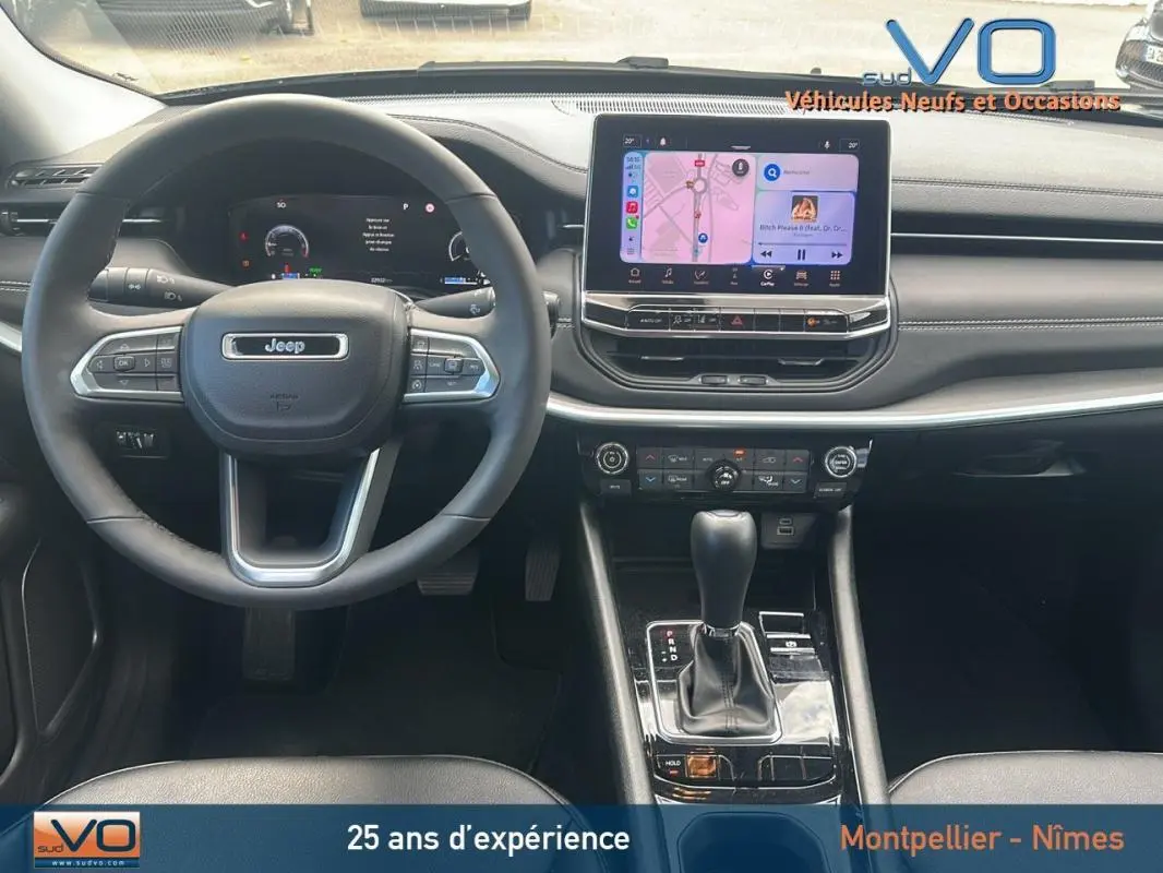 Vue intérieure centrée sur le volant et l'écran tactile du Jeep Compass 2023, finition Limited, avec console et commandes visibles.