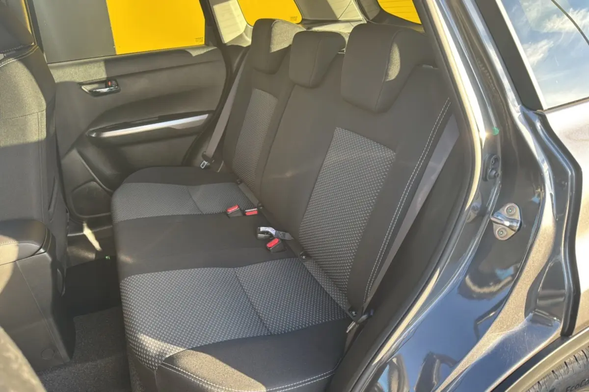 Banquette arrière en tissu gris et noir du Suzuki Vitara Hybrid 110 Privilege AllGrip, vue côté gauche avec portière ouverte.