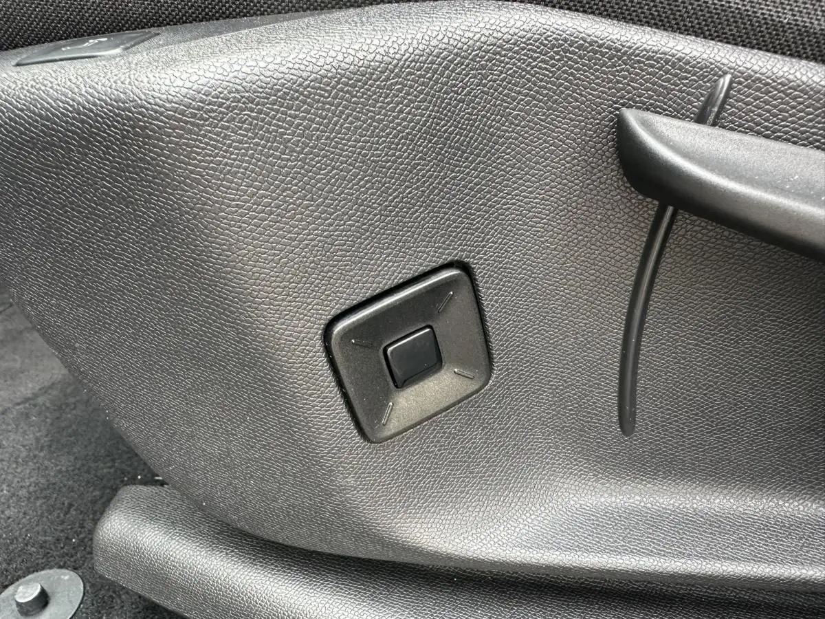 Détail du bouton de réglage manuel noir sur le côté du siège avant du Peugeot 3008 gris Artense 2024.