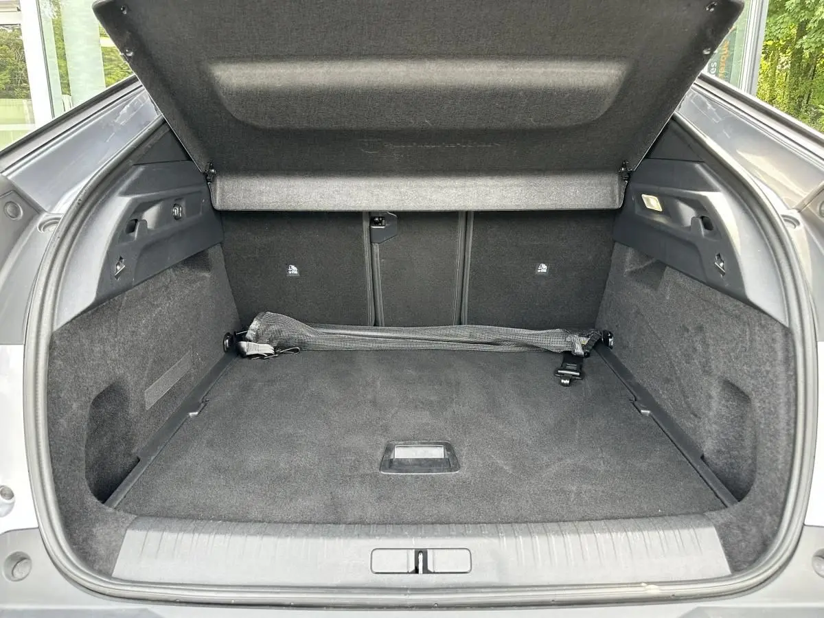 Coffre ouvert vu de l'arrière d'un Peugeot 3008 gris Artense, avec tapis et filet de rangement noir.