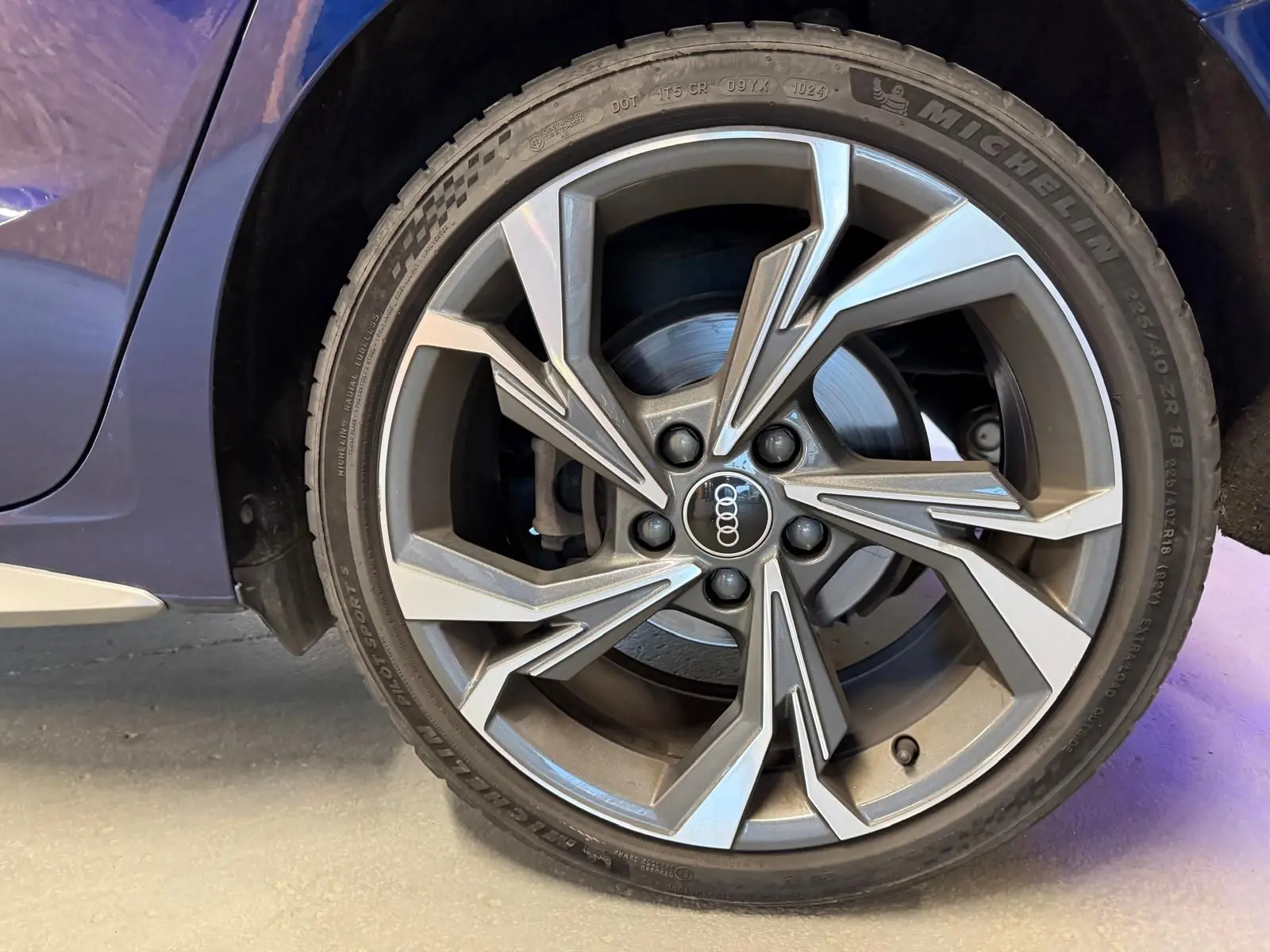 Gros plan sur la roue avant gauche d'une Audi A3 bleu 2022, mettant en valeur la jante alliage au design moderne.