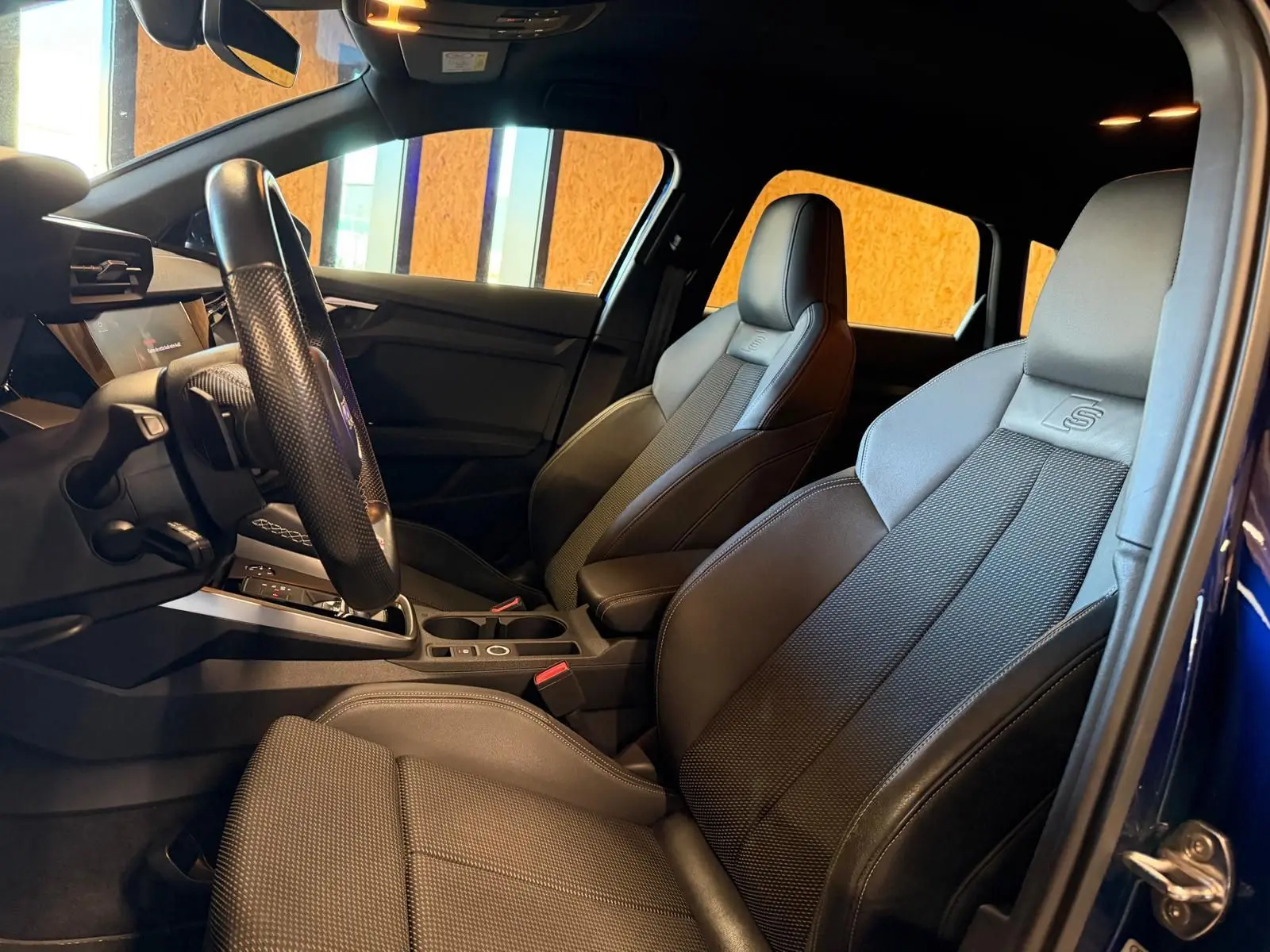 Vue intérieure côté conducteur de l'Audi A3 S-Line 2022 bleu, sièges sport en tissu noir avec logo S embossé.