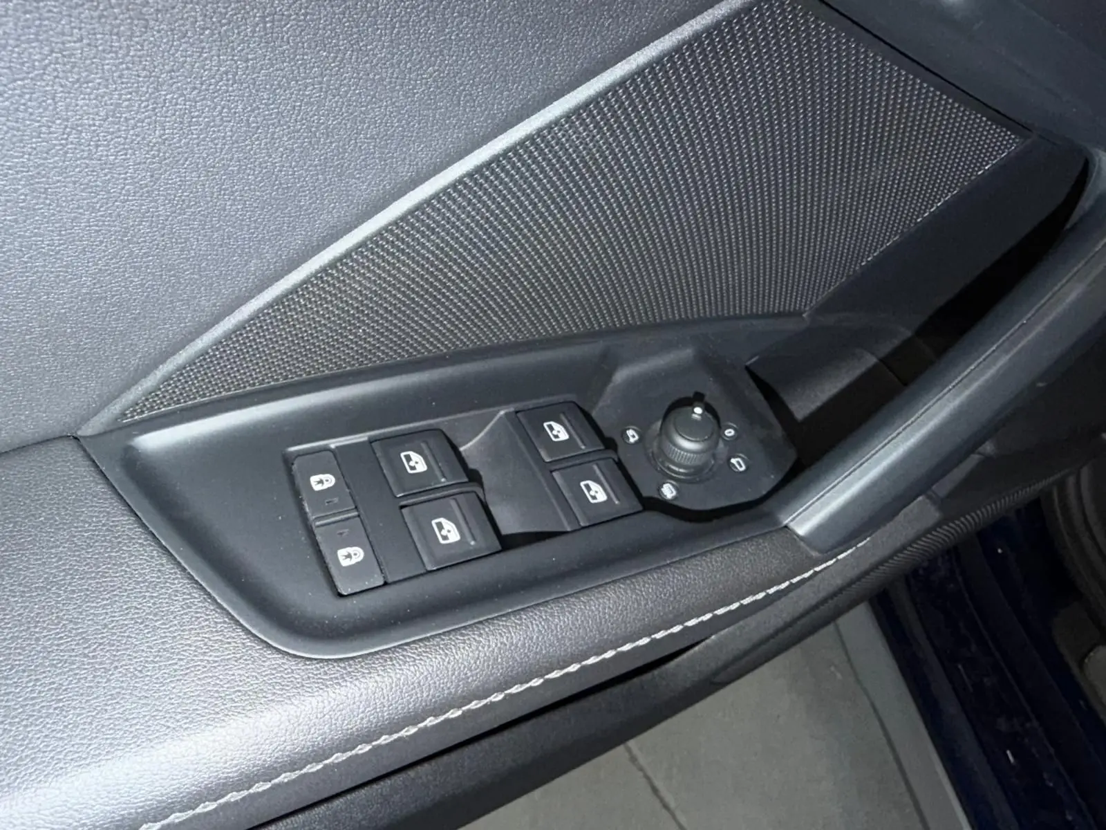 Gros plan sur la commande des vitres et rétroviseurs côté conducteur de l'Audi A3 bleu 2022, finition S-Line.