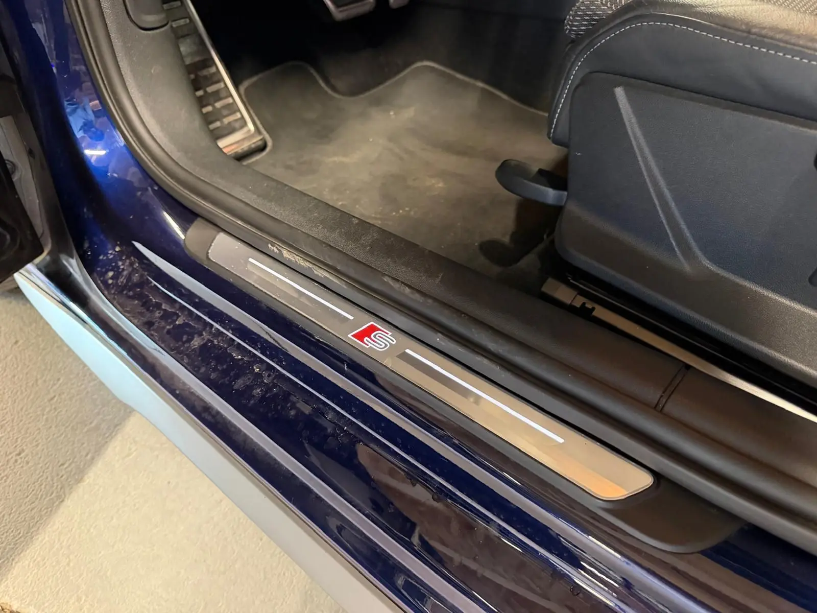 Gros plan sur la porte côté conducteur d’une Audi A3 bleu 2022 avec seuil de porte S-Line et intérieur noir.