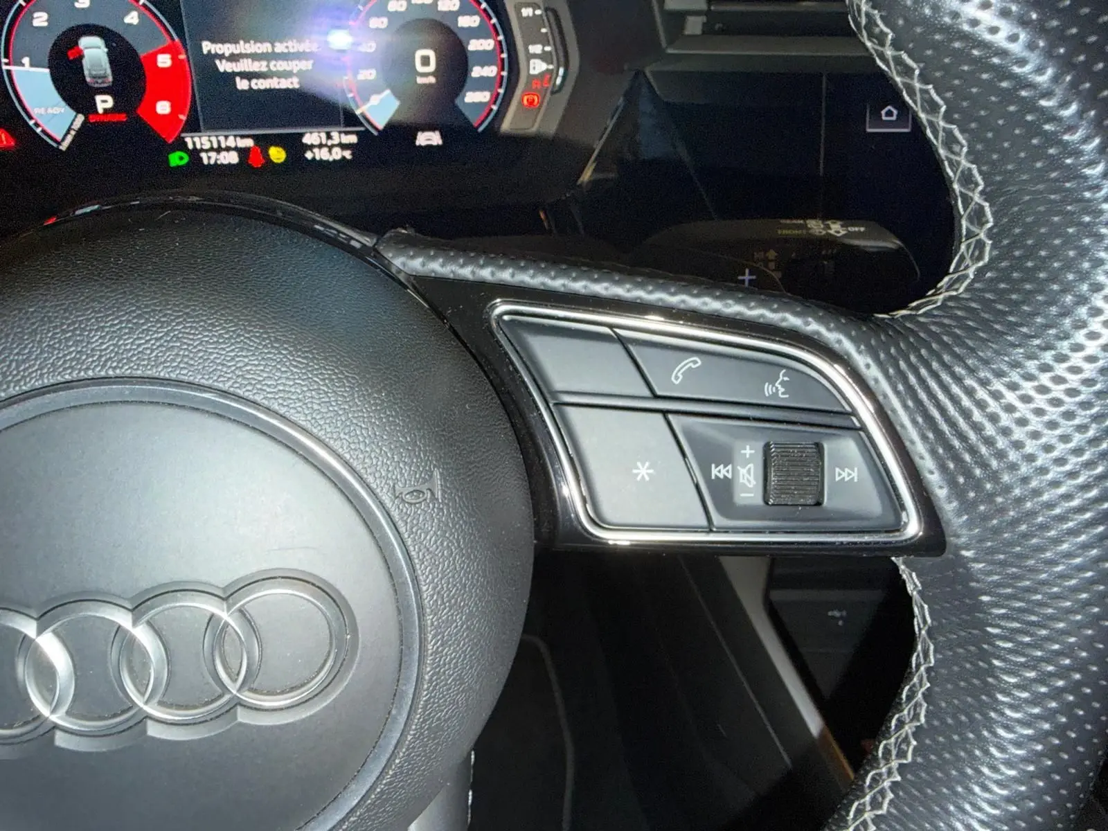 Gros plan sur le volant en cuir perforé de l'Audi A3 bleu 2022, avec commandes intégrées côté droit.