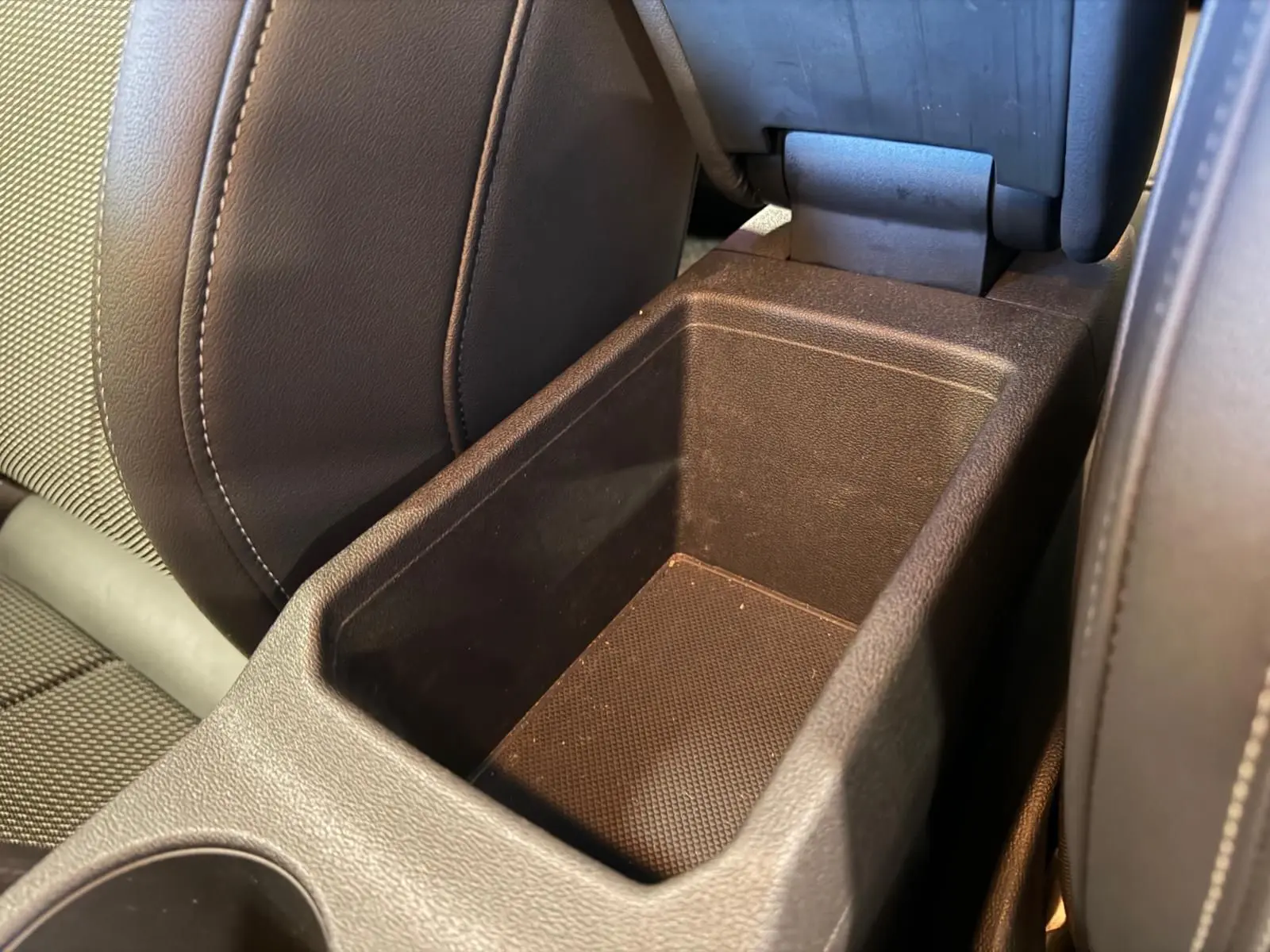 Gros plan sur le rangement central entre les sièges avant en tissu noir de l’Audi A3 2.0 TDI S-Line 2022.