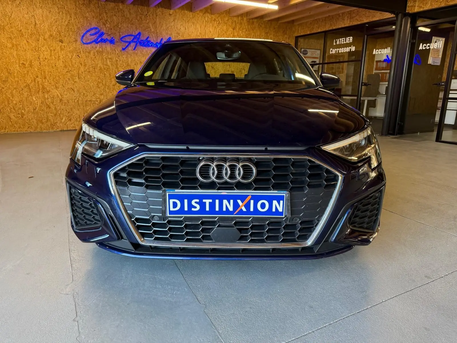 Vue frontale d'une Audi A3 2.0 TDI S-Line bleu foncé avec calandre hexagonale et logo Audi visible en intérieur.