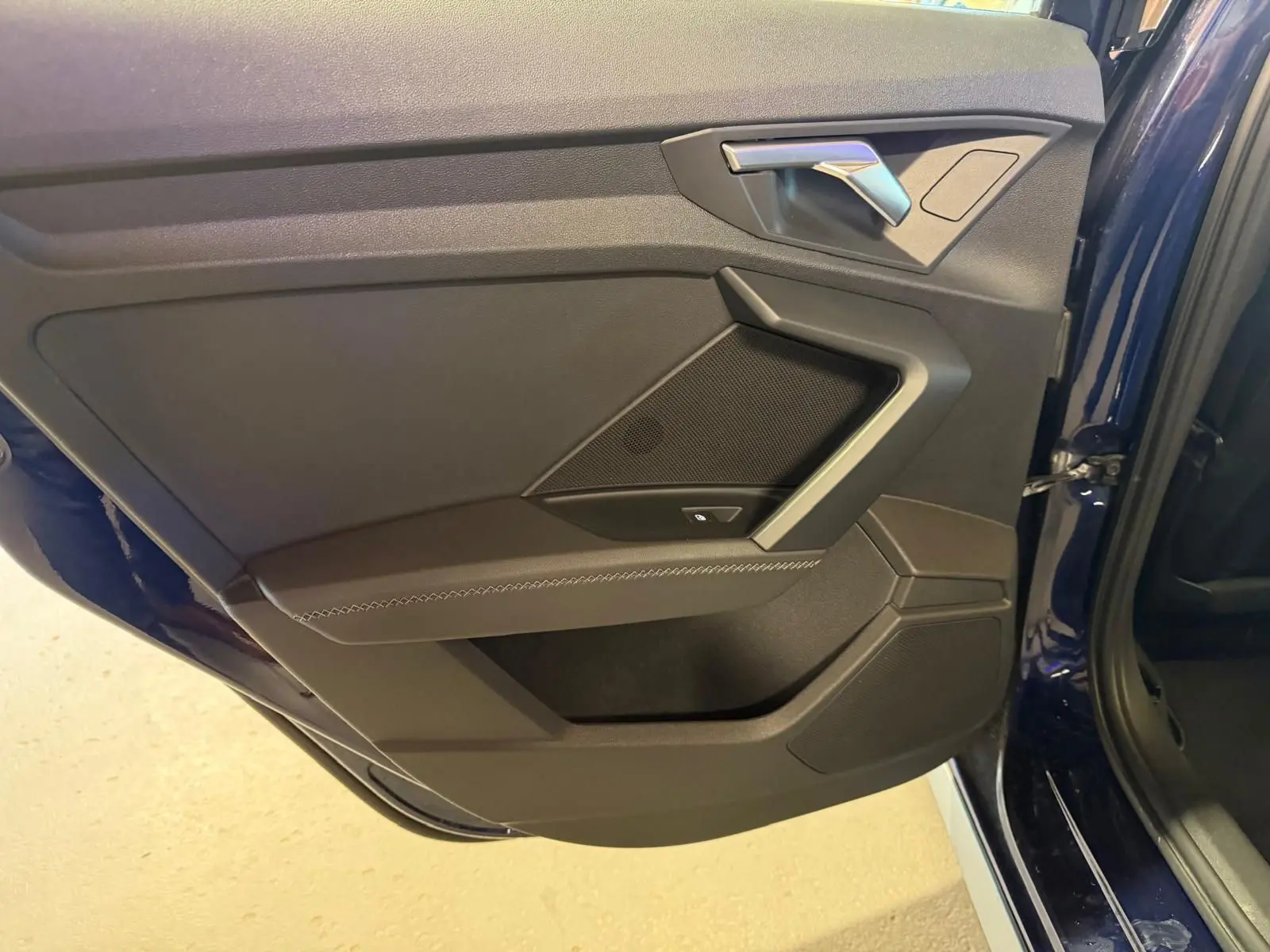 Vue rapprochée de la porte arrière droite bleu foncé d’une Audi A3 2.0 TDI 150 S-Line, avec garniture noire et poignée argentée.