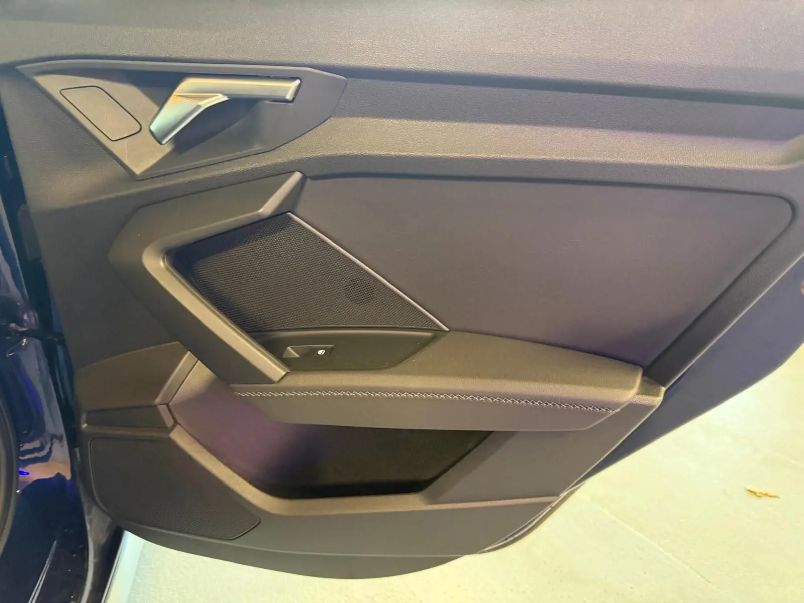 Vue rapprochée de la porte avant gauche de l'Audi A3 2.0 TDI S-Line bleu, avec poignée argentée et panneau noir.