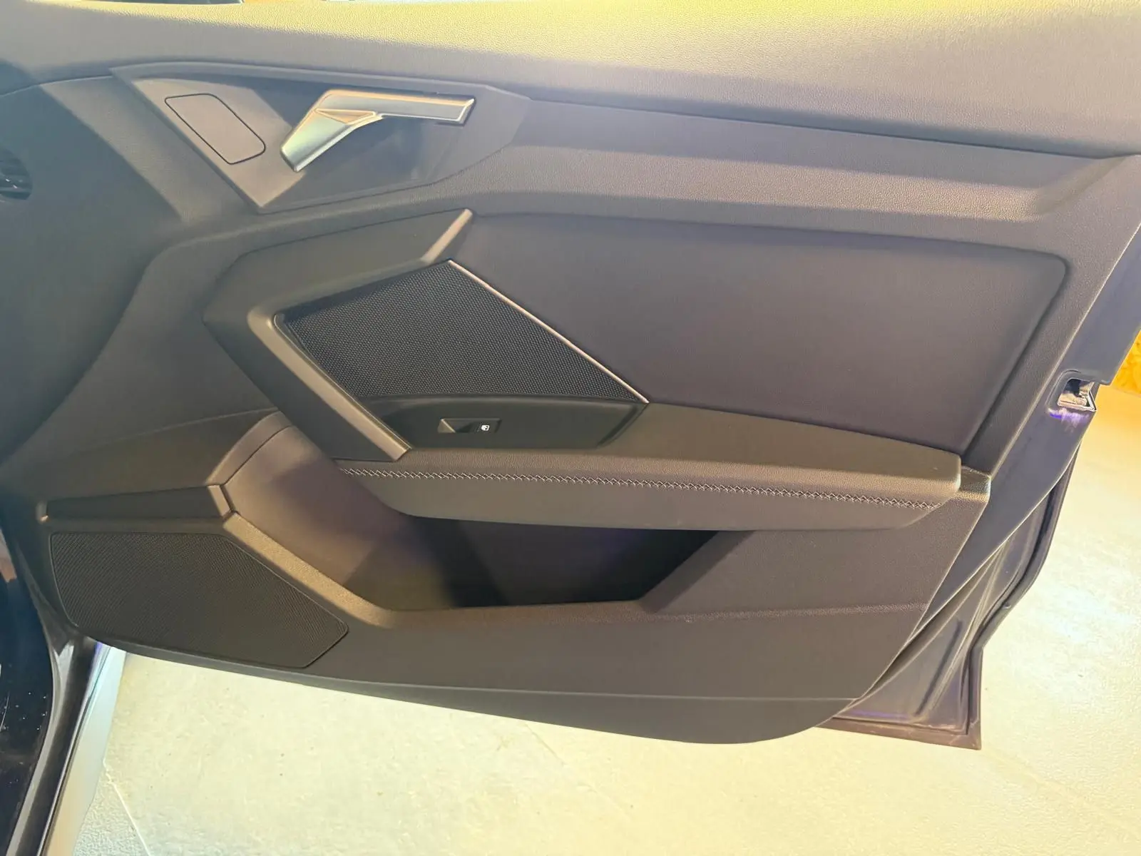 Vue rapprochée de la porte avant gauche de l’Audi A3 2.0 TDI 150 S-TRONIC S-LINE bleu, intérieur noir avec poignée argentée.