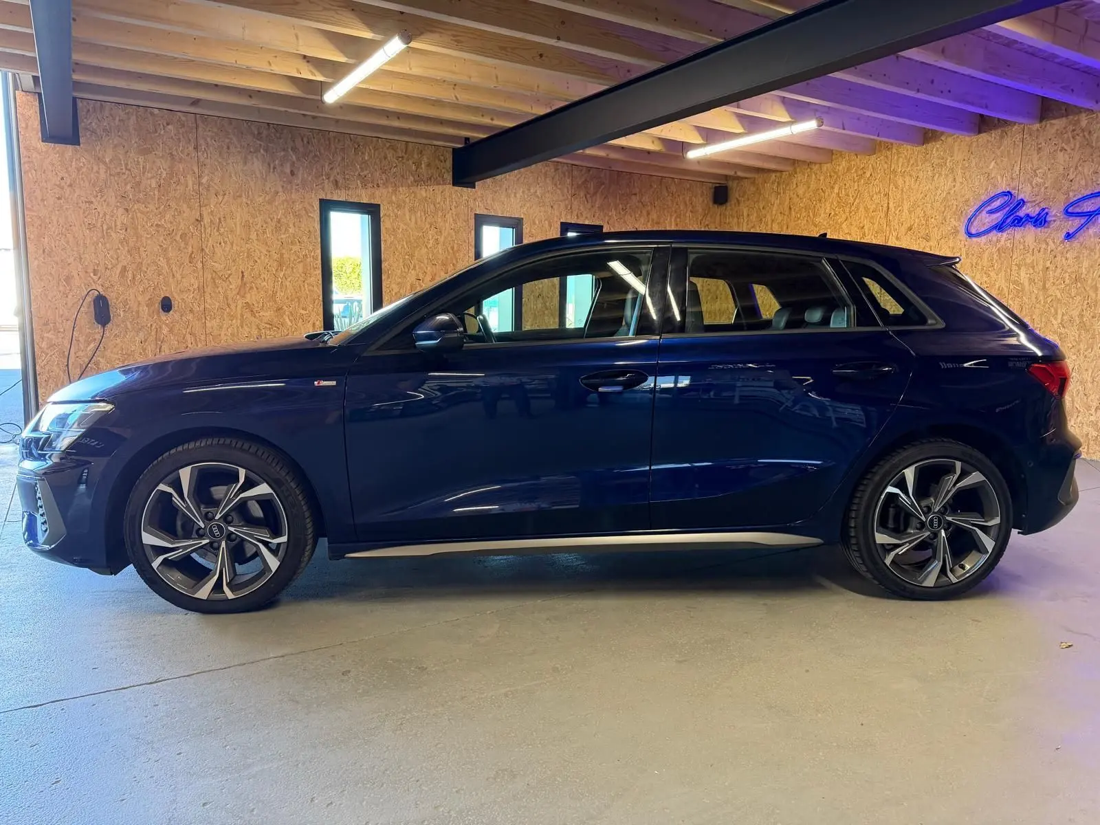 Audi A3 2.0 TDI S-Line bleu vue de profil côté gauche, avec jantes alliage distinctives en intérieur bois.