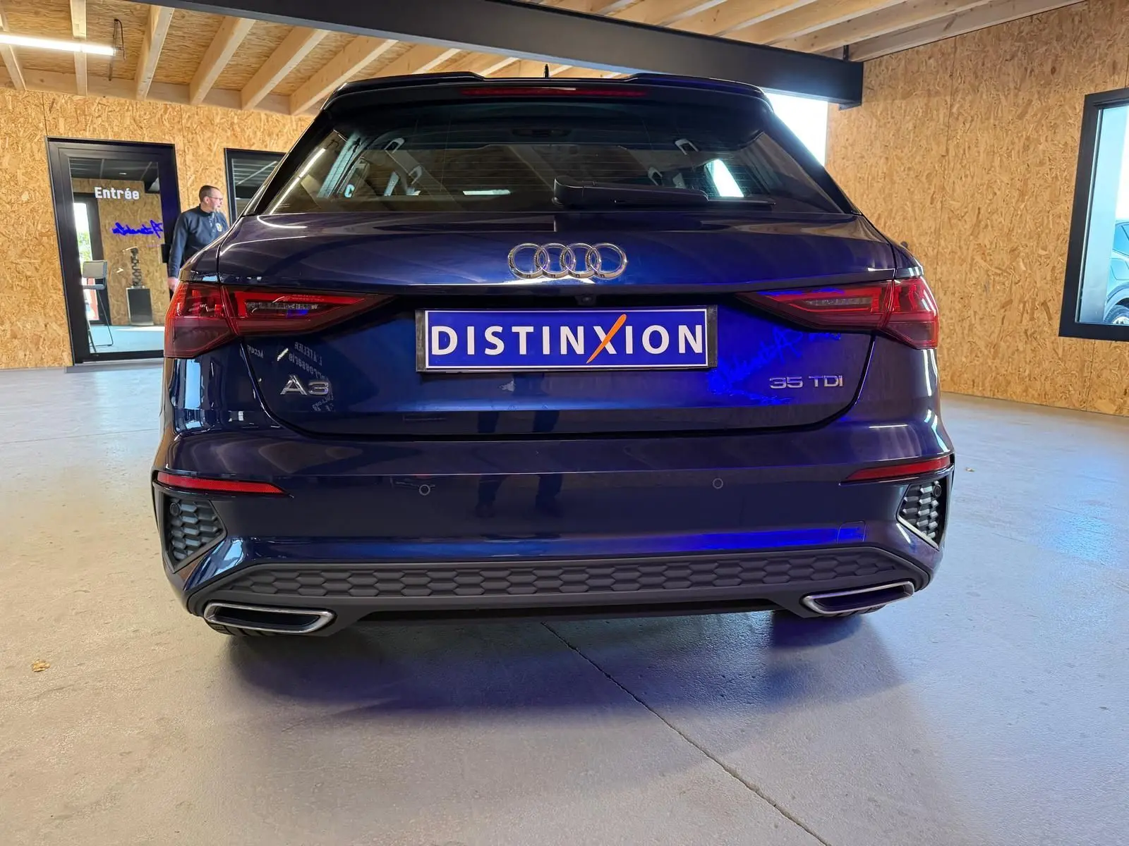 Vue arrière d'une Audi A3 bleu foncé 2022 avec logo et double sortie d'échappement intégrée au pare-chocs.