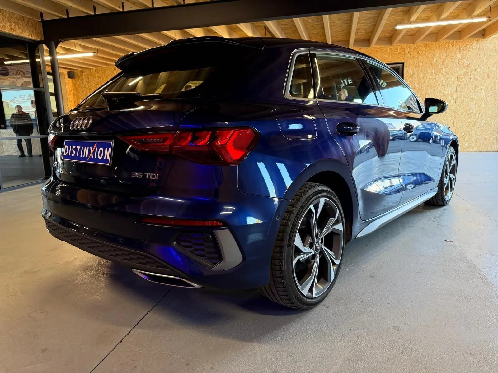 Audi A3 2.0 TDI bleu vue 3/4 arrière droit, avec jantes alliage et feux arrière LED distinctifs.