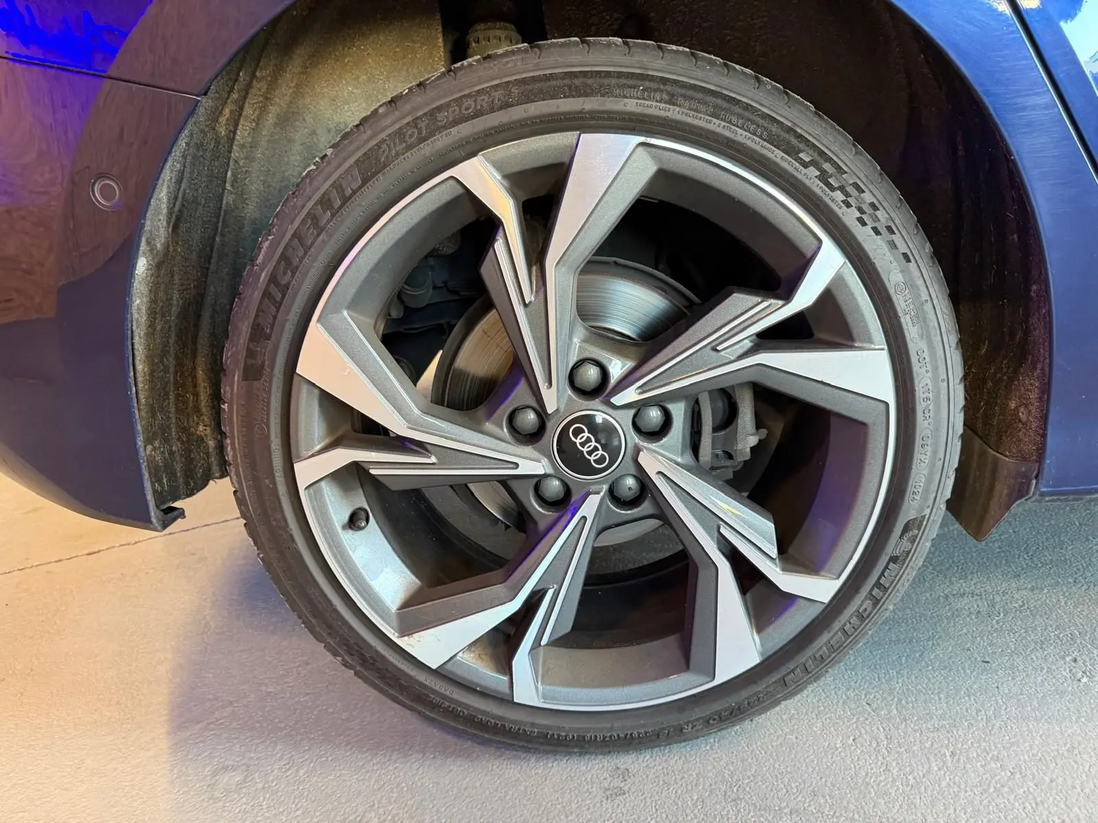 Gros plan sur la roue avant gauche d'une Audi A3 bleu 2022 avec jante alliage au design moderne.