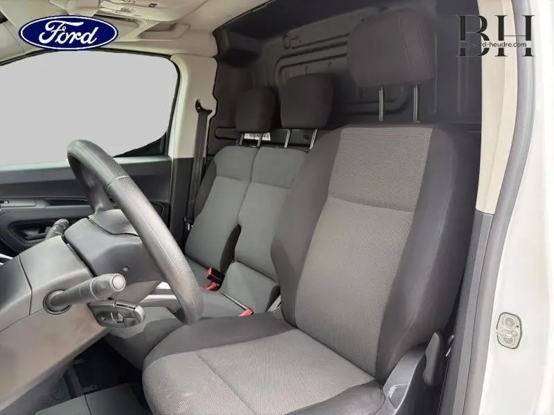 Vue intérieure côté conducteur du Citroën Berlingo Fourgon 2020, sièges tissu gris et volant multifonction.