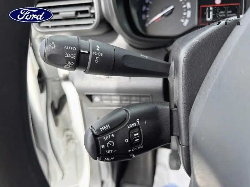 Gros plan sur les commandes au volant du Citroën Berlingo Fourgon blanc Banquise, avec régulateur et feux visibles.