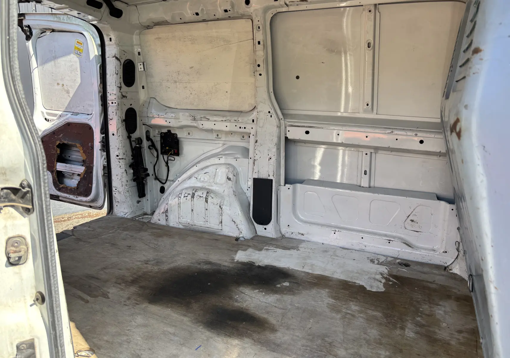 Intérieur arrière du fourgon blanc Fiat Scudo II 2010, vue côté gauche avec plancher usé et porte ouverte.