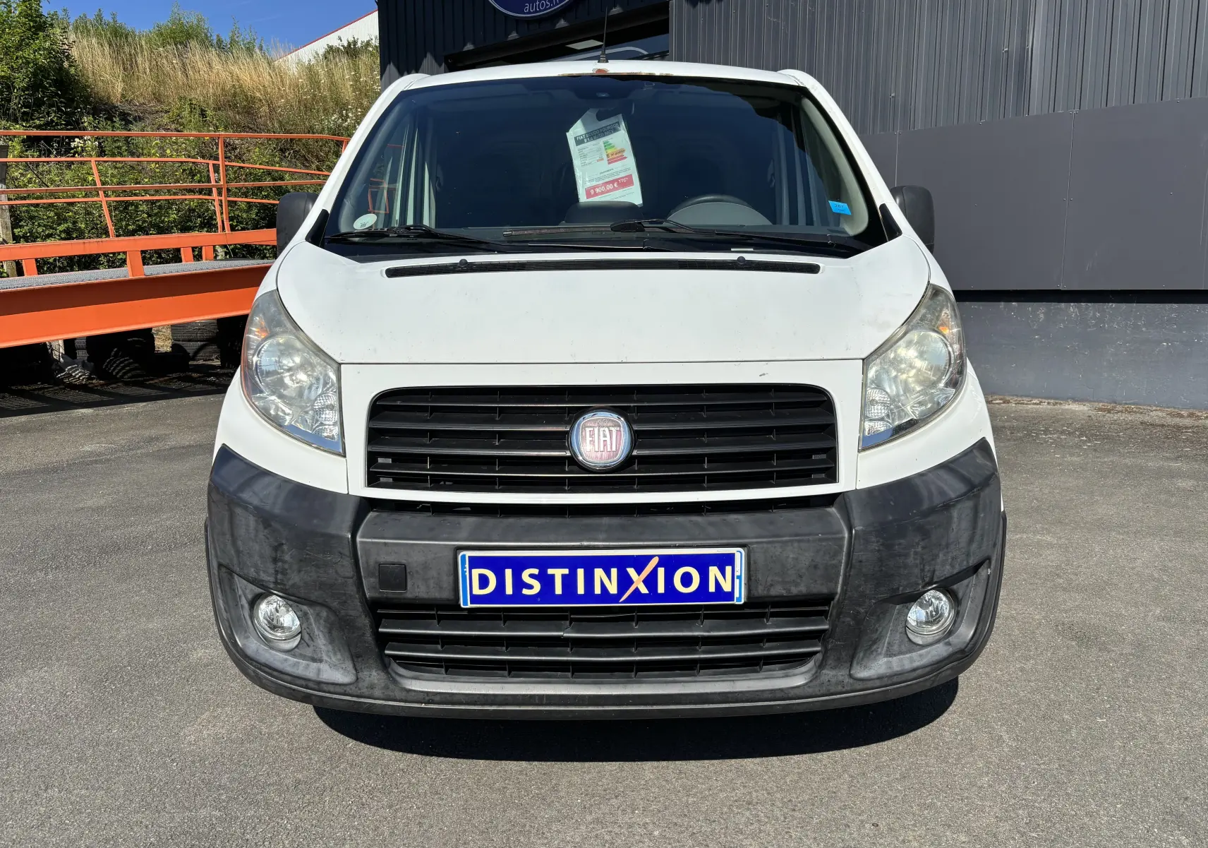 Vue frontale d'un fourgon FIAT Scudo blanc de 2010 avec pare-chocs noir et plaque Distinxion visible.