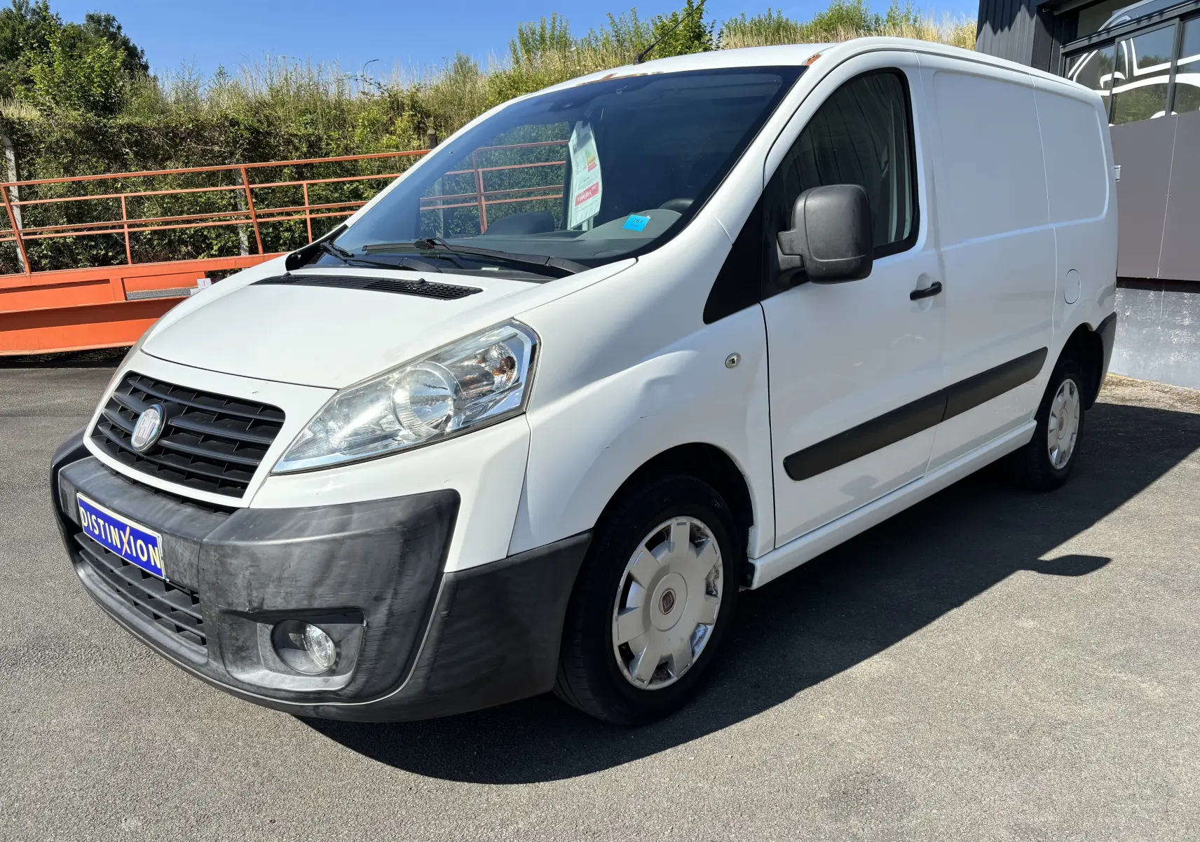 Fourgon blanc Fiat Scudo II 1.6 MJTD vu en 3/4 avant droit, avec pare-chocs noir et jantes d'origine.