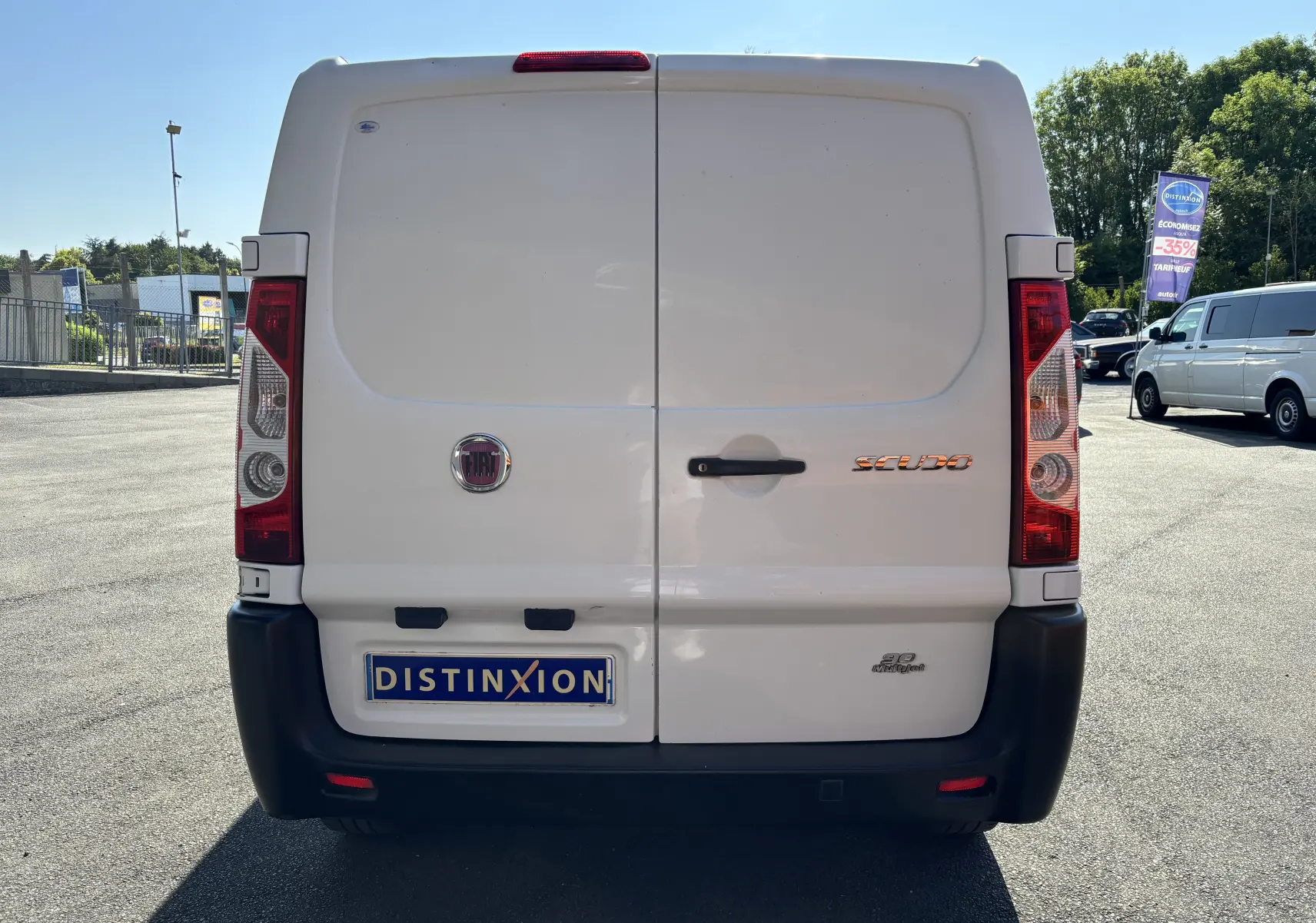 Vue arrière d'un fourgon blanc FIAT Scudo II 1.6 MJTD 90CV de 2010 avec logo et plaque Distinxion.