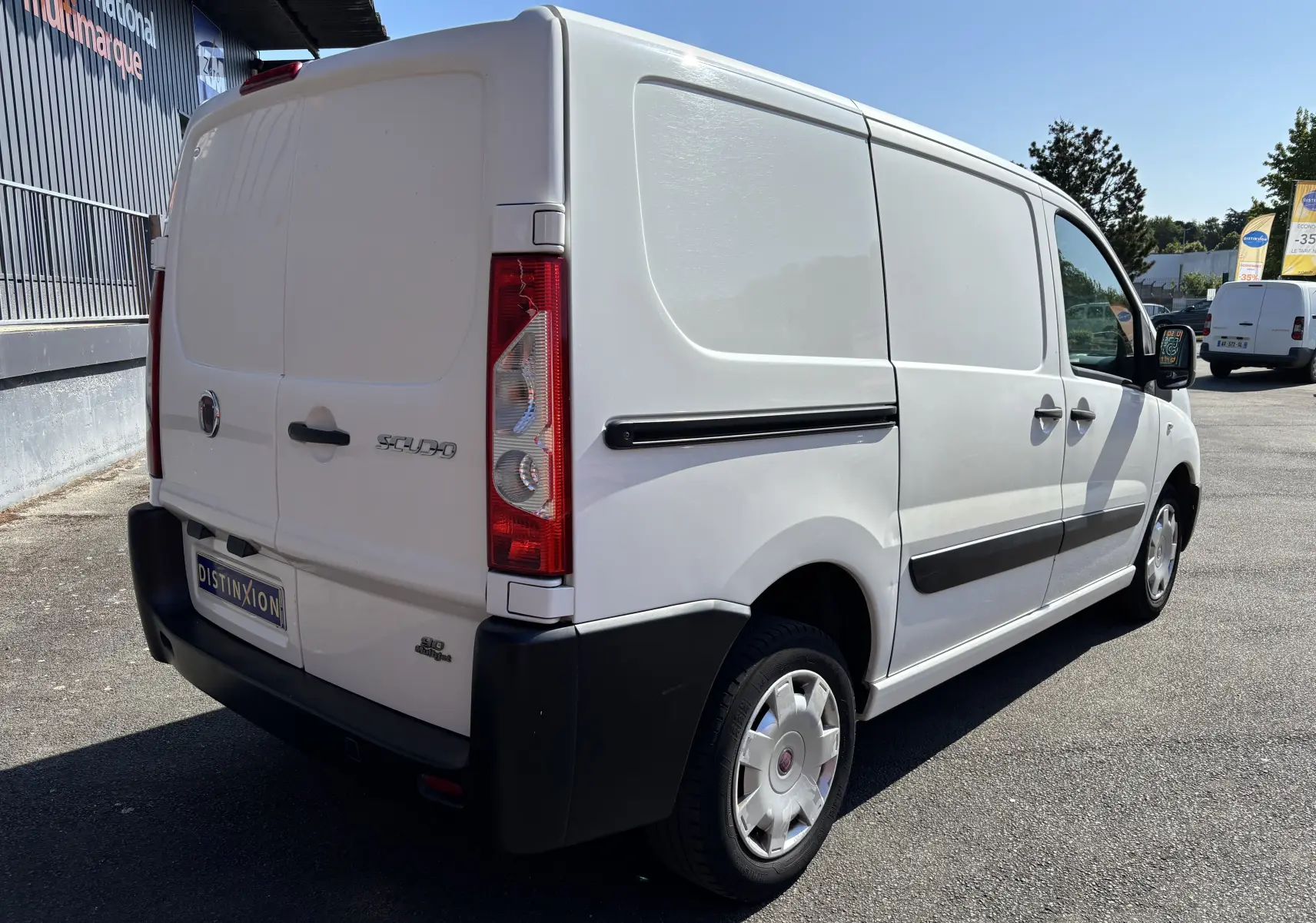 Fiat Scudo Fourgon blanc vu en 3/4 arrière droit, avec portes arrière battantes et protections latérales noires.