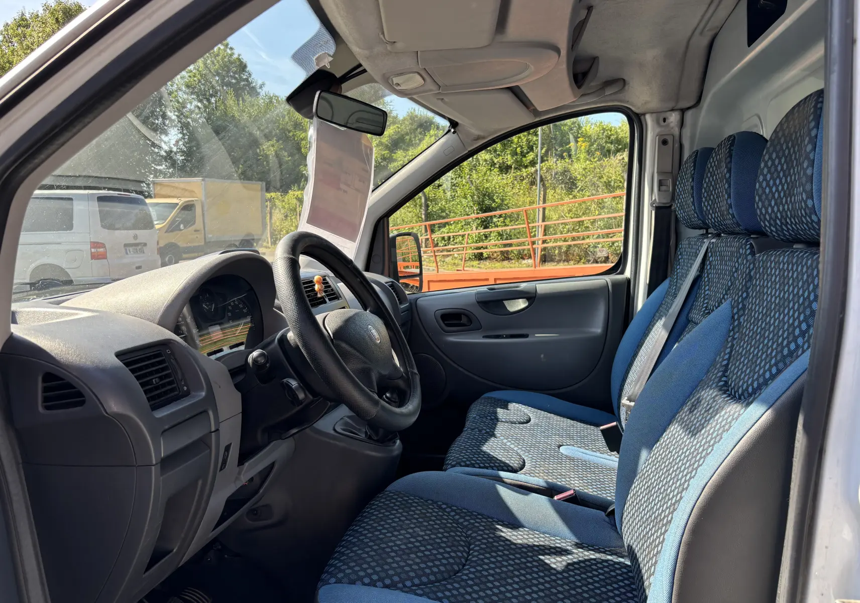 Intérieur du FIAT Scudo Fourgon blanc vu côté gauche, montrant le tableau de bord et sièges bleus à motifs.