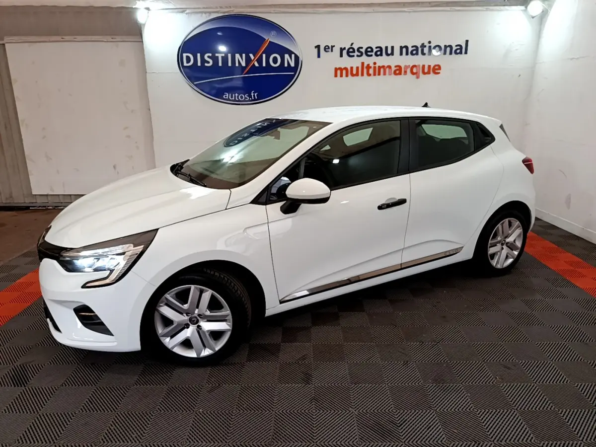 Vue 3/4 avant droite d'une Renault Clio Business blanche 2021 en intérieur avec feux LED allumés.