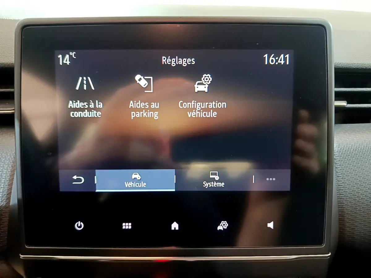 Écran tactile central de la Renault Clio Business blanc, affichant les réglages d'aides à la conduite et parking.