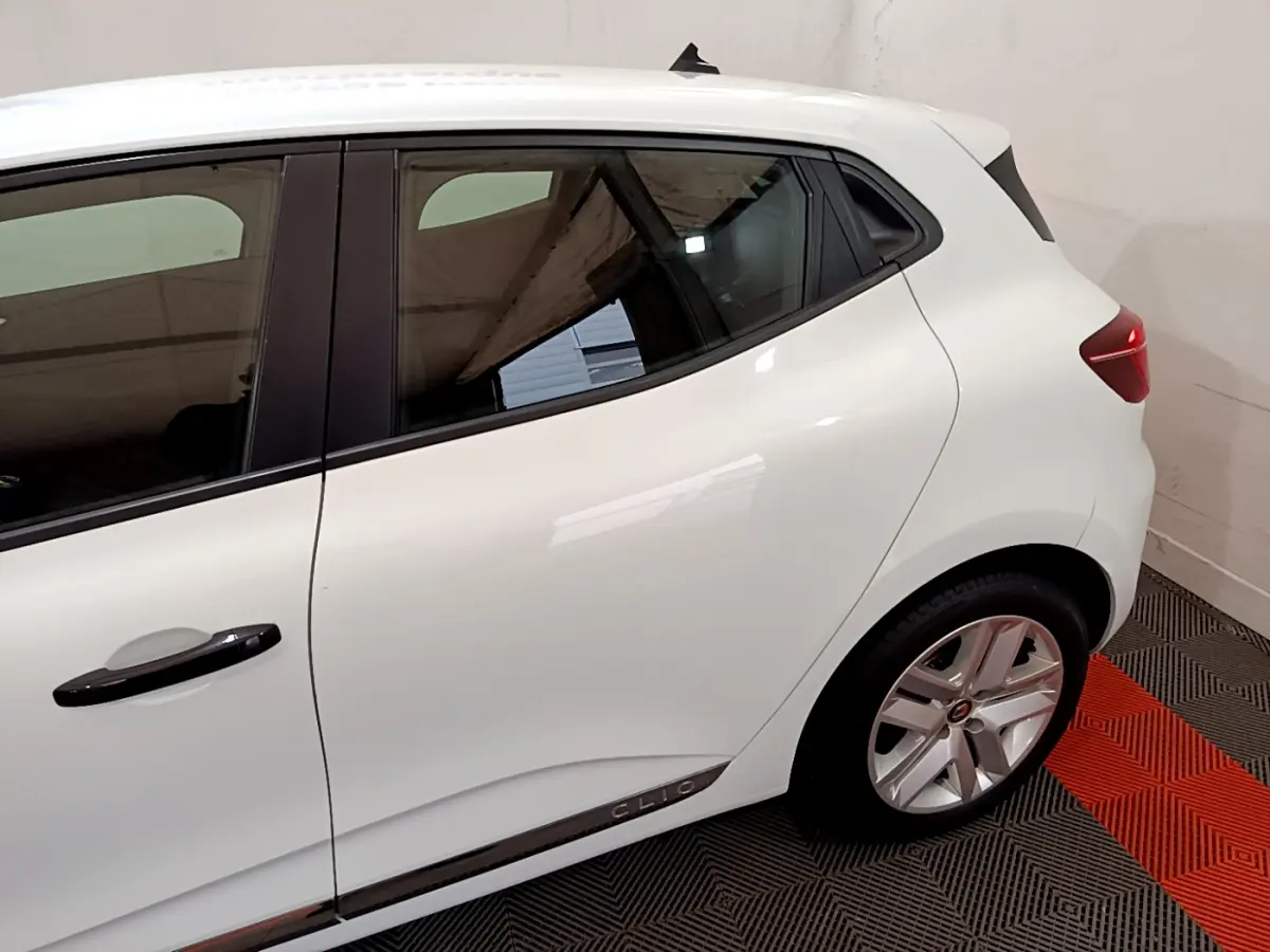 Vue latérale côté gauche d'une Renault Clio blanche avec poignées noires et jantes alliage visibles.