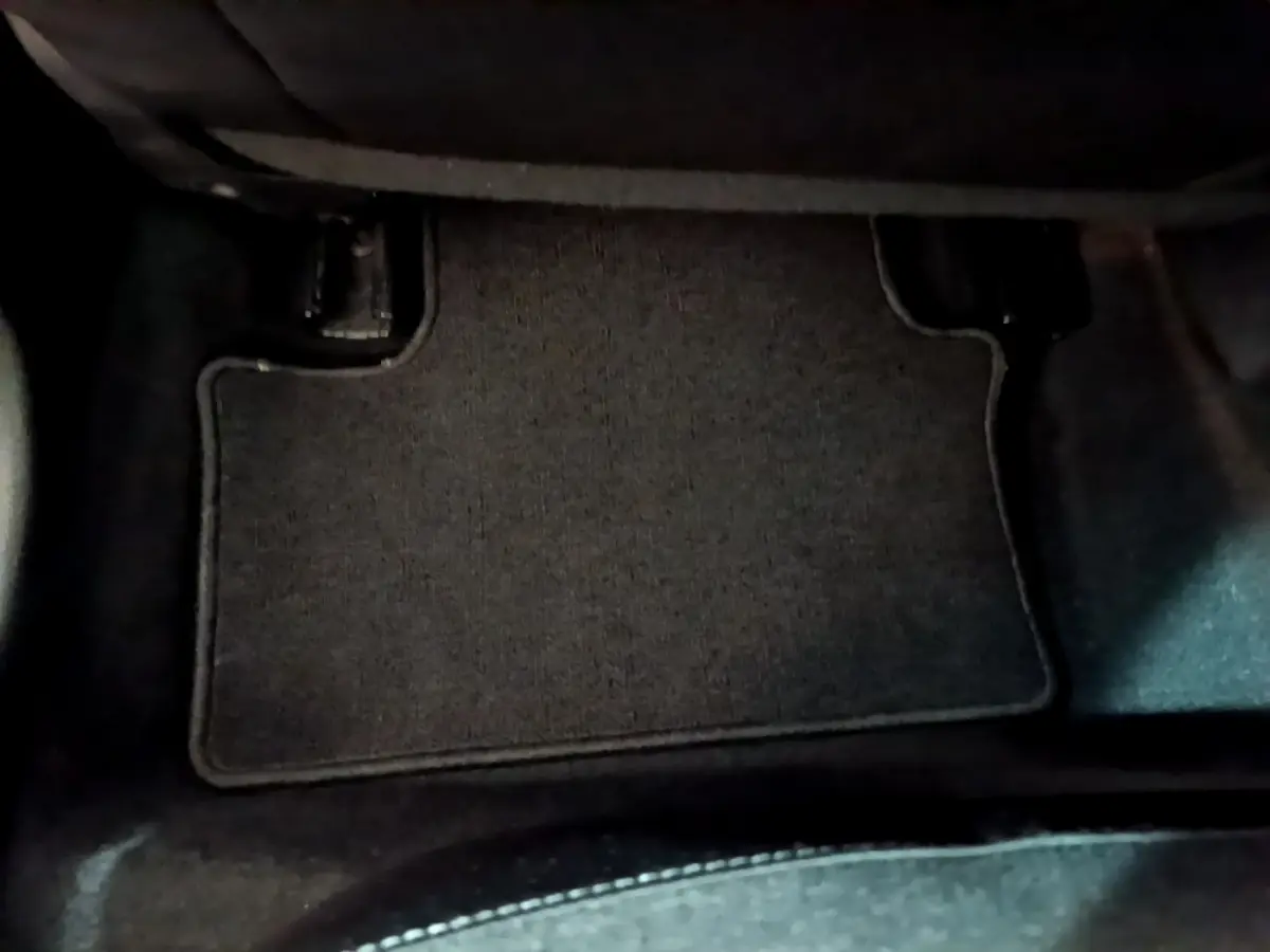 Tapis de sol noir côté passager avant de la Renault Clio Business blanche vue en gros plan intérieur.