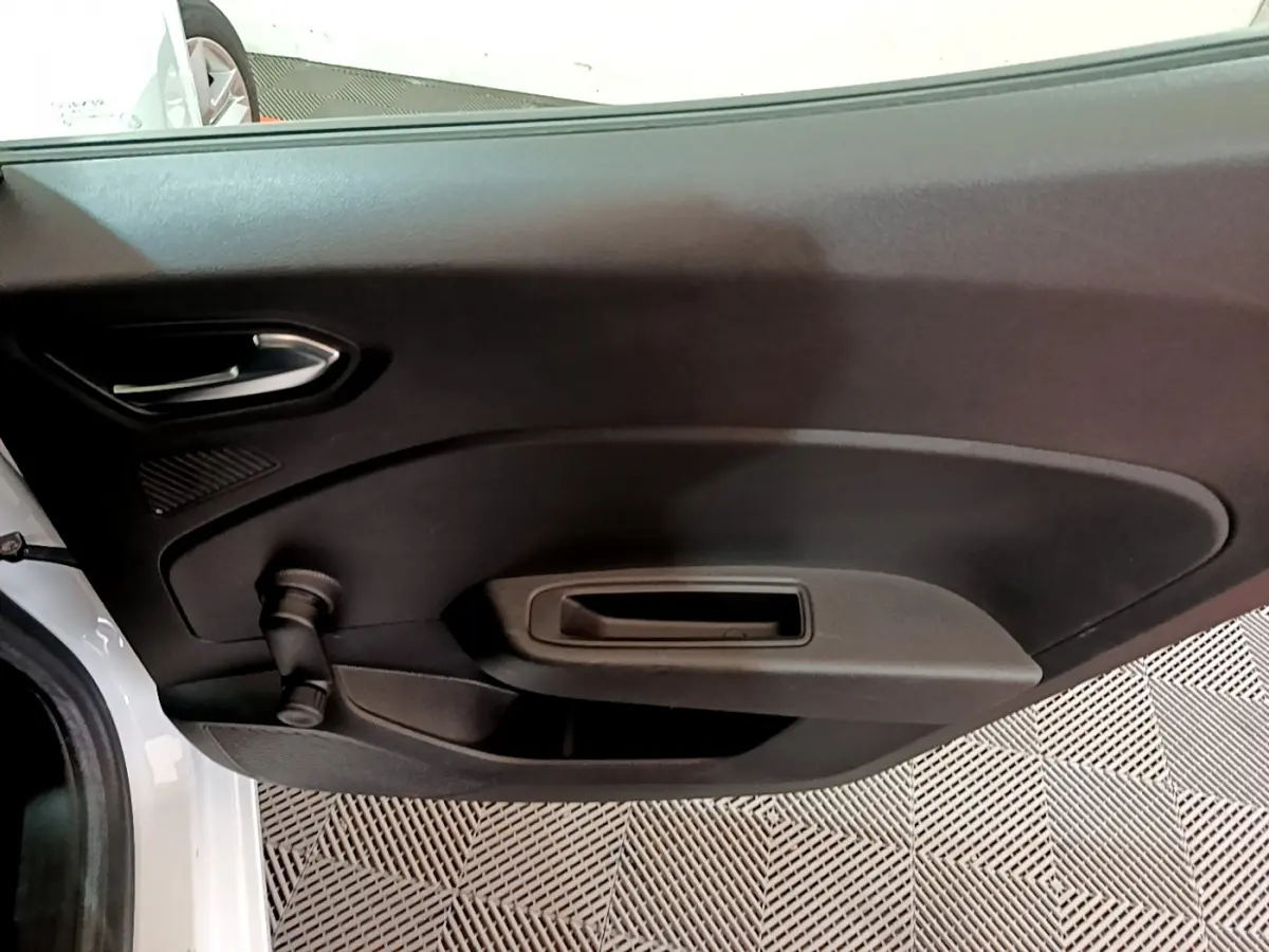 Vue rapprochée de la porte intérieure côté gauche d'une Renault Clio Business blanche avec poignée et manivelle de vitre.